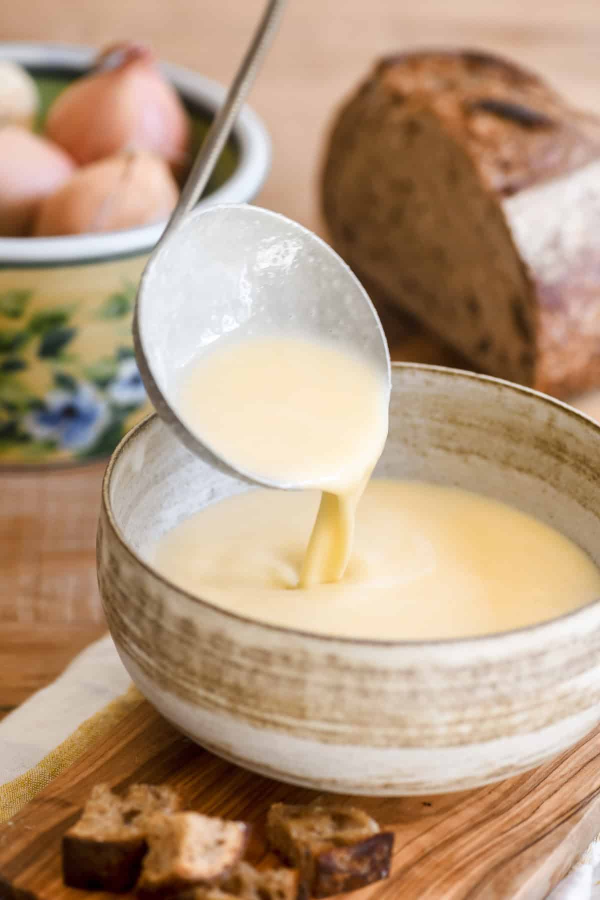 Ladling cheese fondue soup into a bowl.