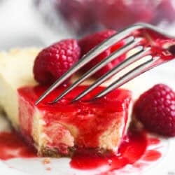 Taking a bite of a slice of fromage blanc cheesecake topped with raspberry coulis.