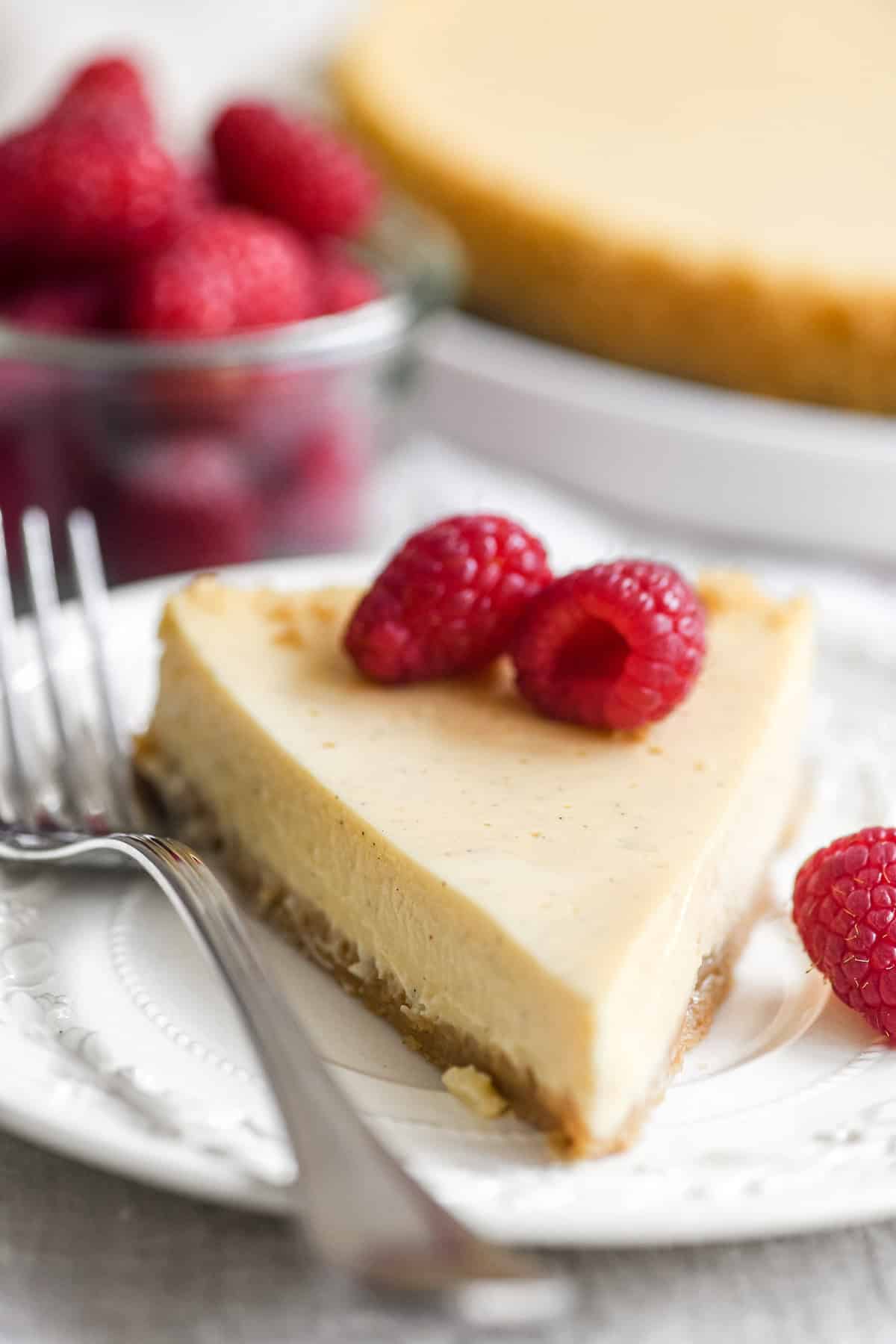 A slice of French fromage blanc cheesecake topped with fresh raspberries.