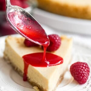 Spooning simple raspberry coulis onto a slice of fromage blanc cheesecake.