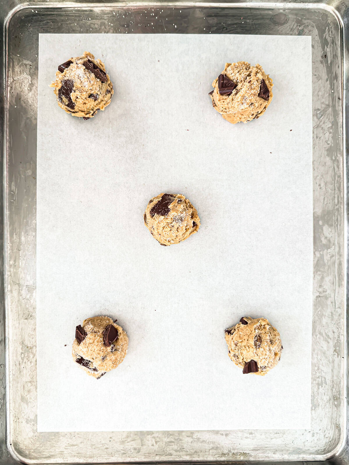 scooped balls of peanut butter chocolate chip cookie dough on pan ready to bake.