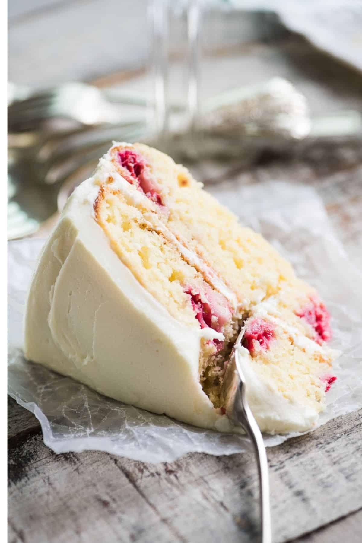 A slice of Raspberry lemon layer cake with fork taking a bite.