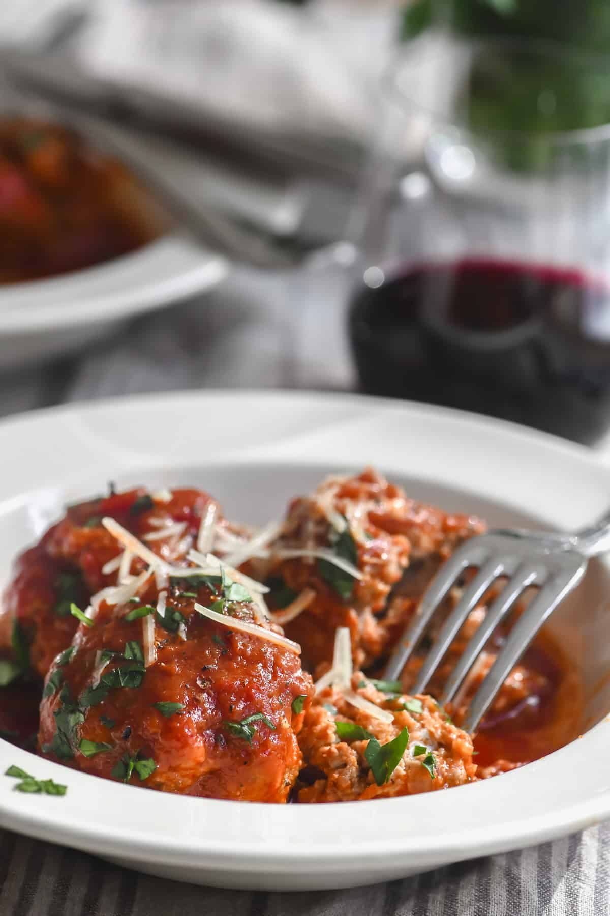 Taking a bite of ricotta meatballs, served in a shallow bowl with sauce, the Italian way.