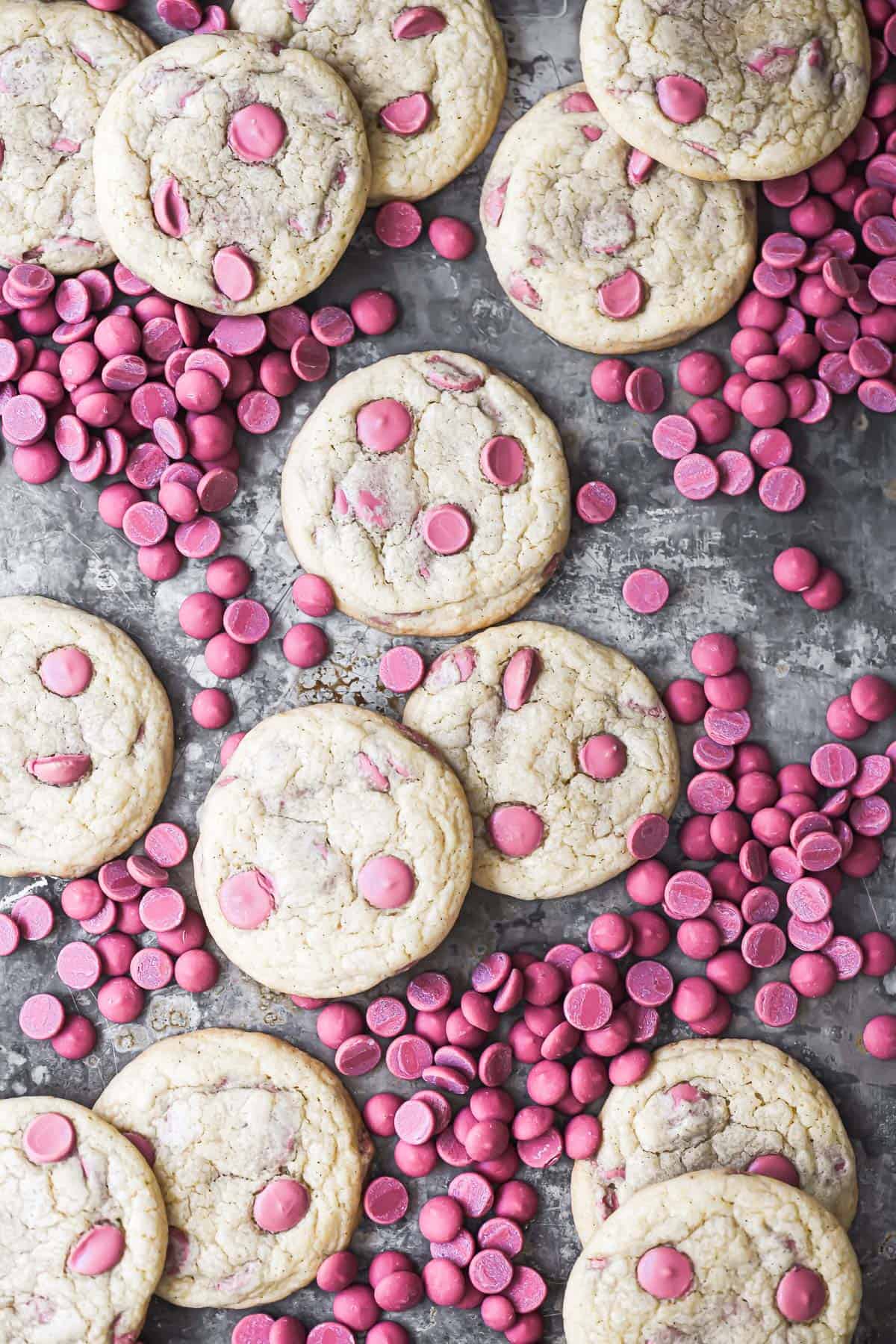 ruby chocolate chip cookies on a baking sheet surrounded by ruby chocolate chips.