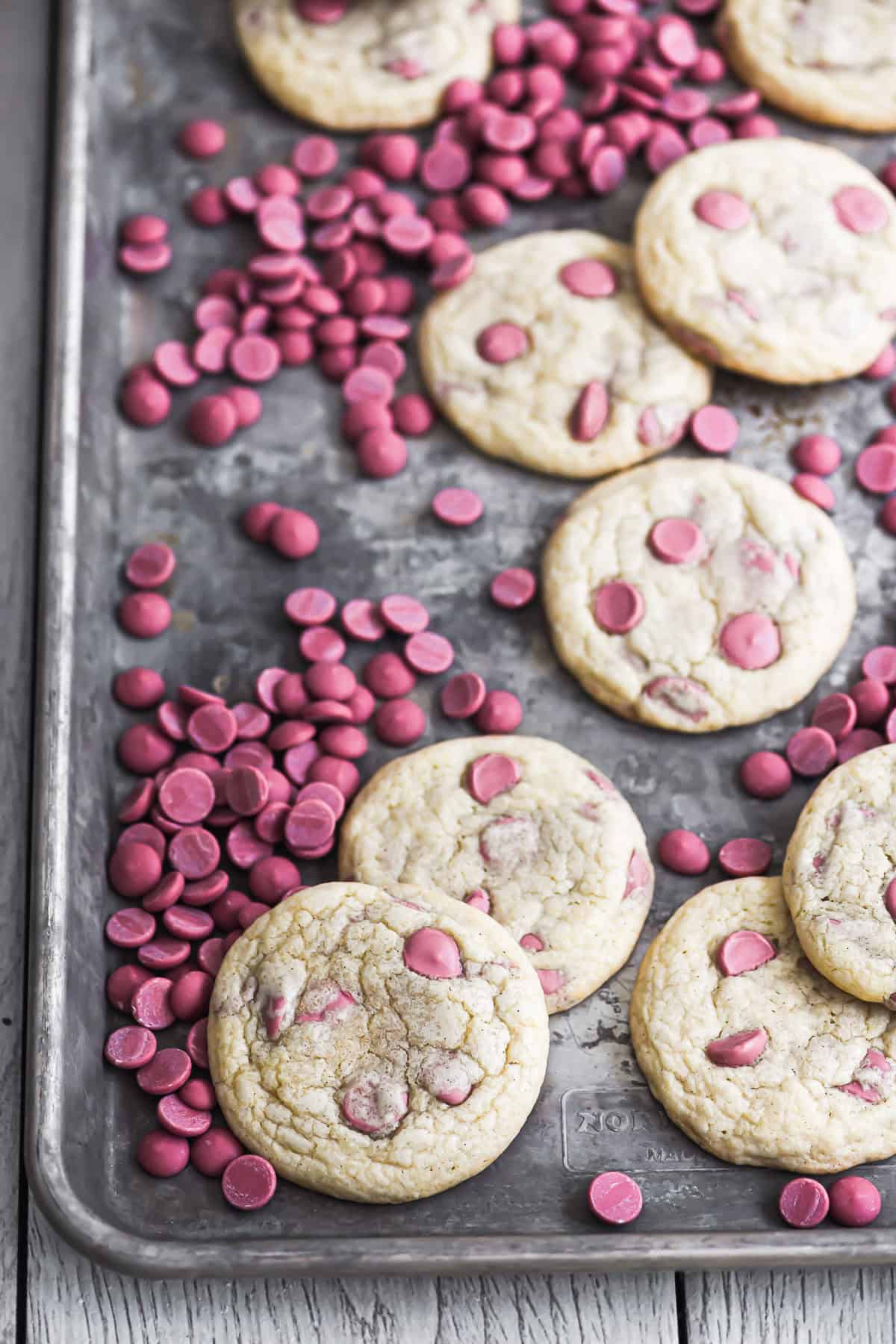 Ruby chocolate chip cookies on a baking sheet with ruby chocolate chips.