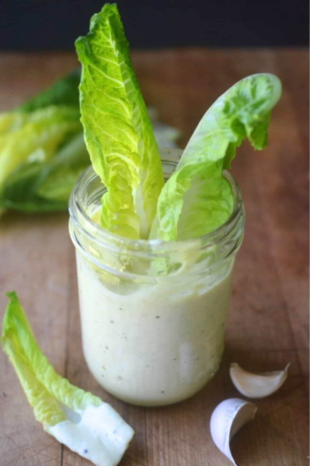 dipping salad greens into a jar of homemade salad dressing.