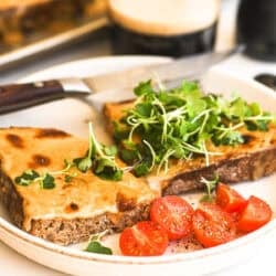 welsh rarebit topped with micro greens on a plate with a glass of Guinness.
