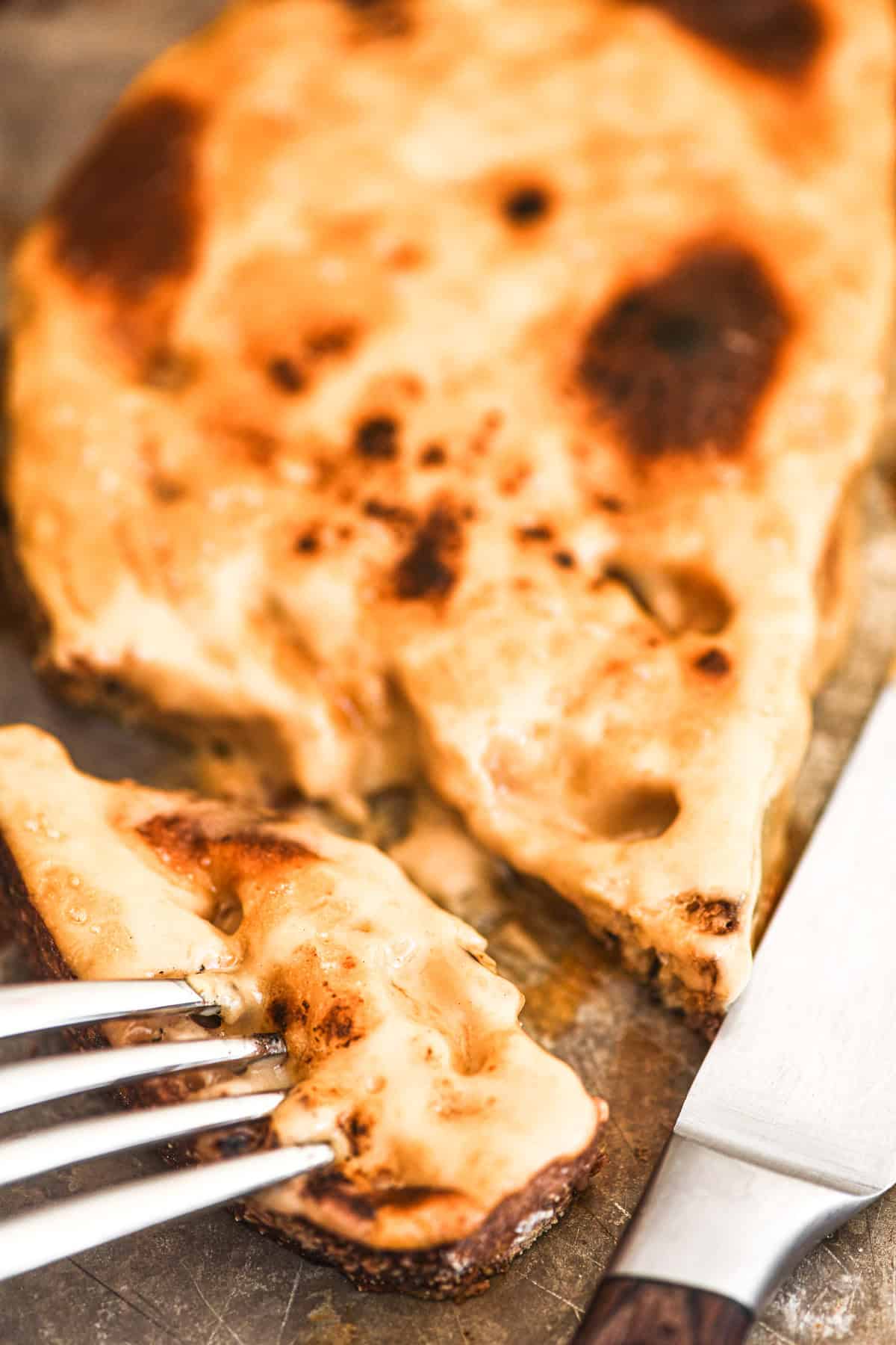 taking a bite of Welsh rarebit, on a baking sheet.