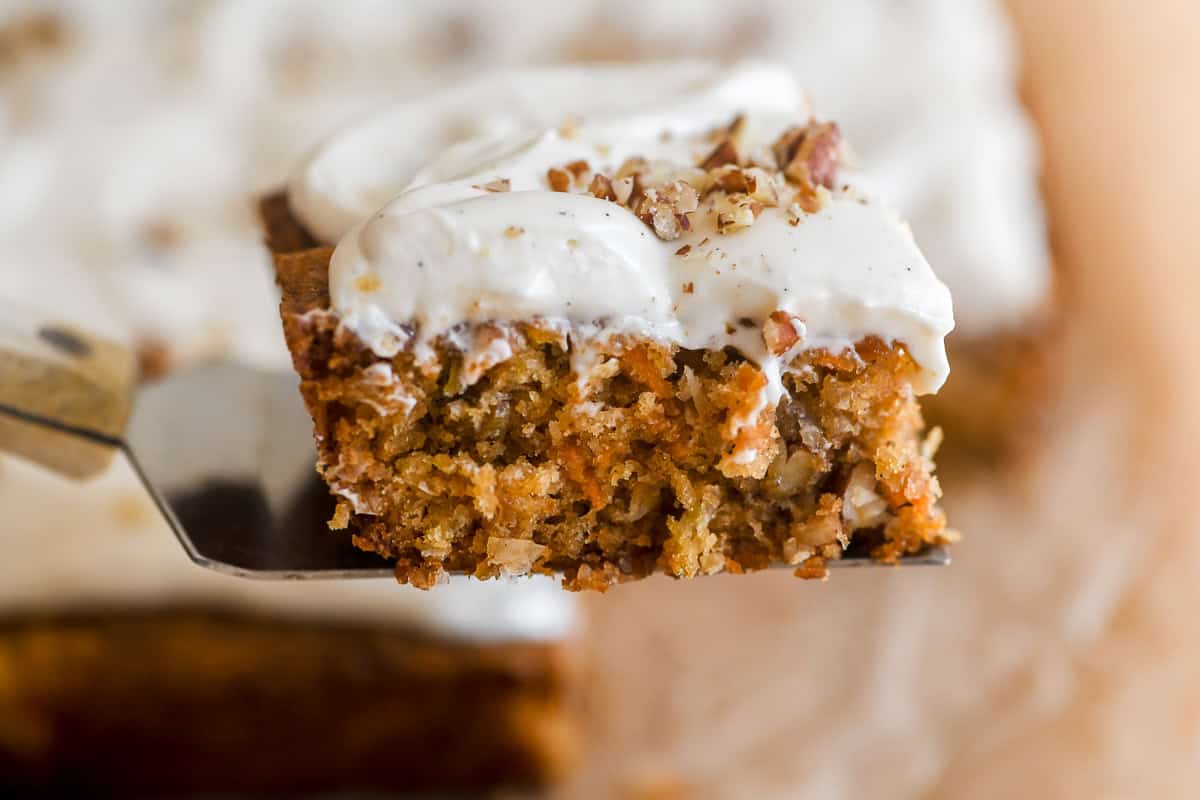 carrot cake bar topped with cream cheese frosting and toasted pecans.