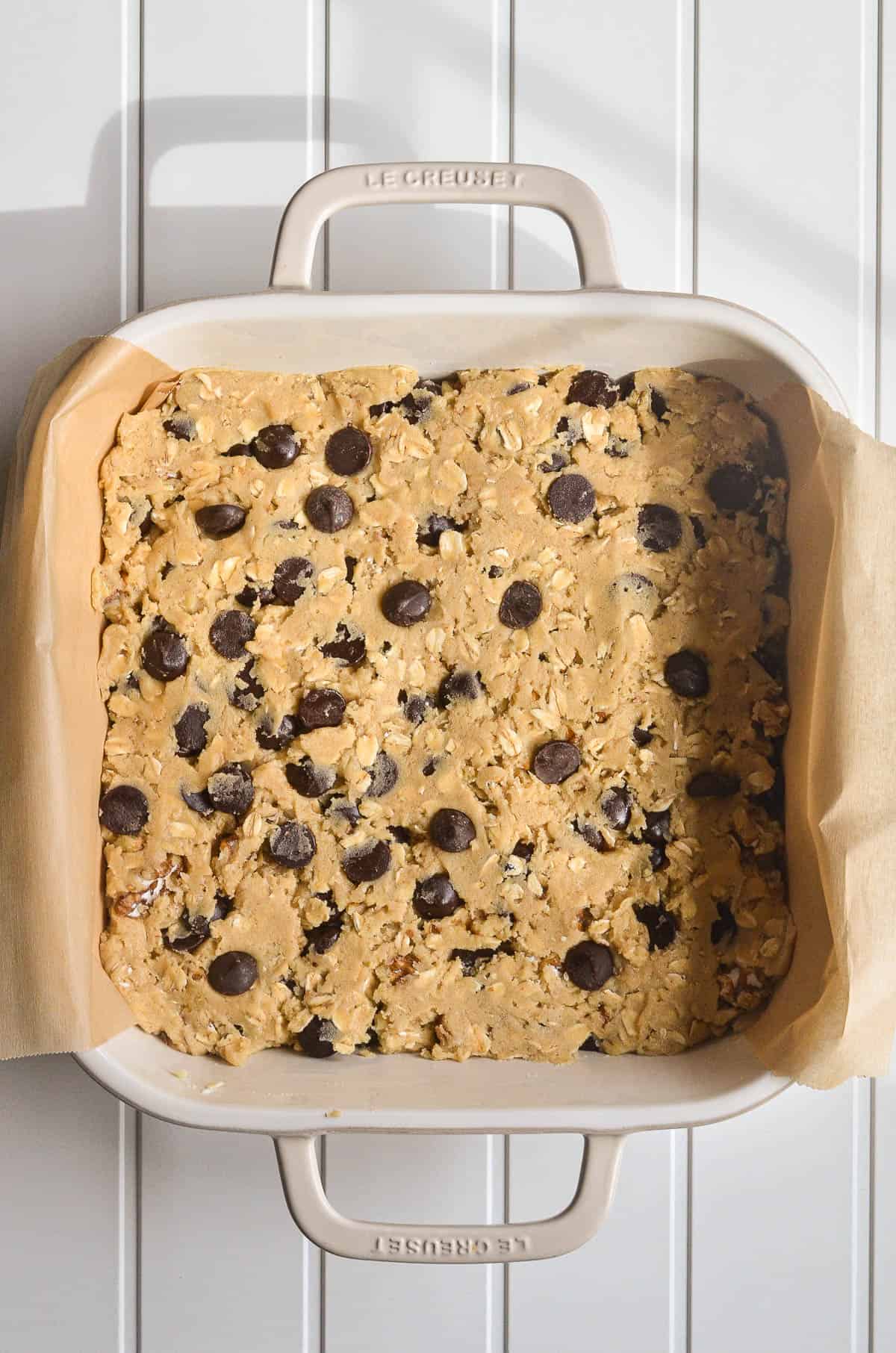 Oatmeal cookie bar dough pressed into a baking pan.
