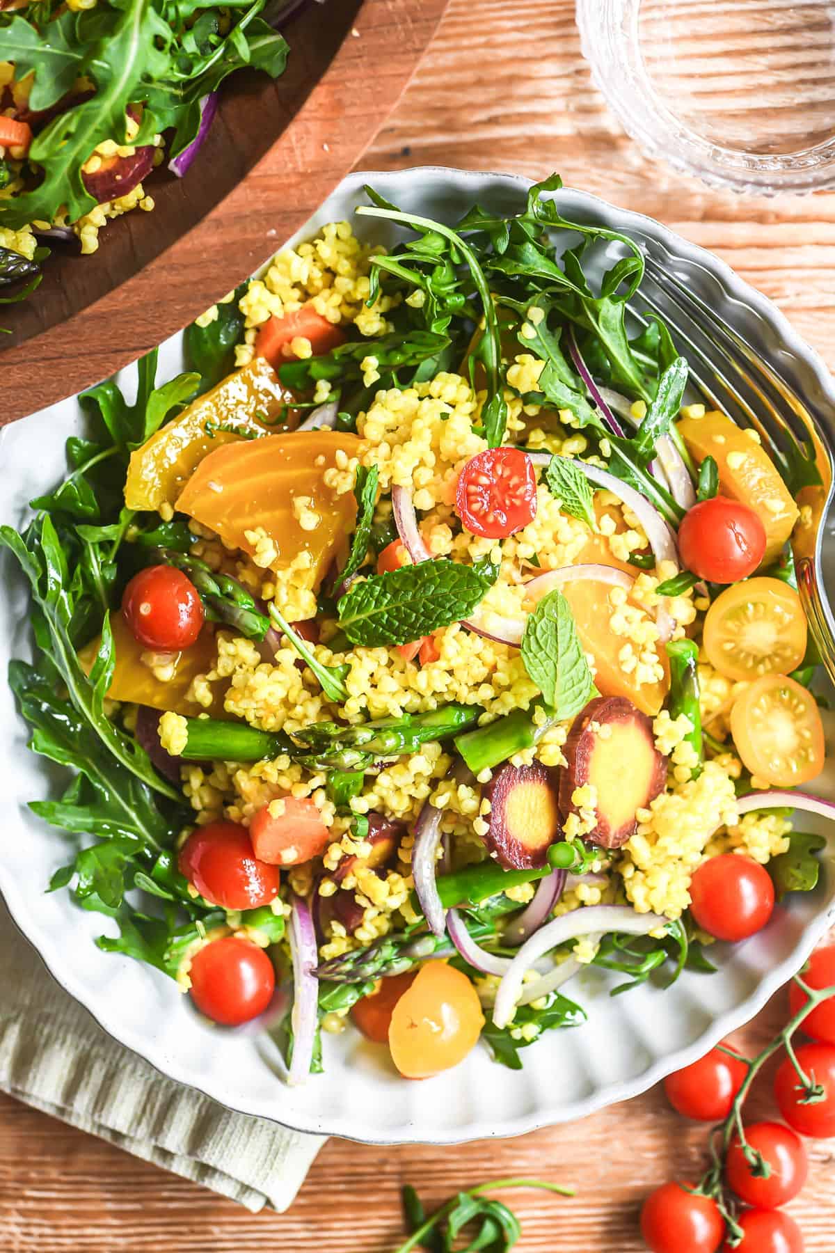 millet salad in a bowl with spring veggies and arugula.