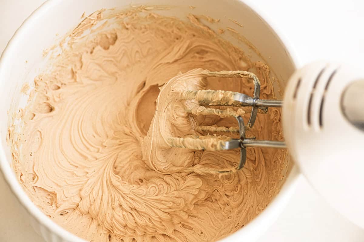 Beating peanut butter buttercream with electric beaters.