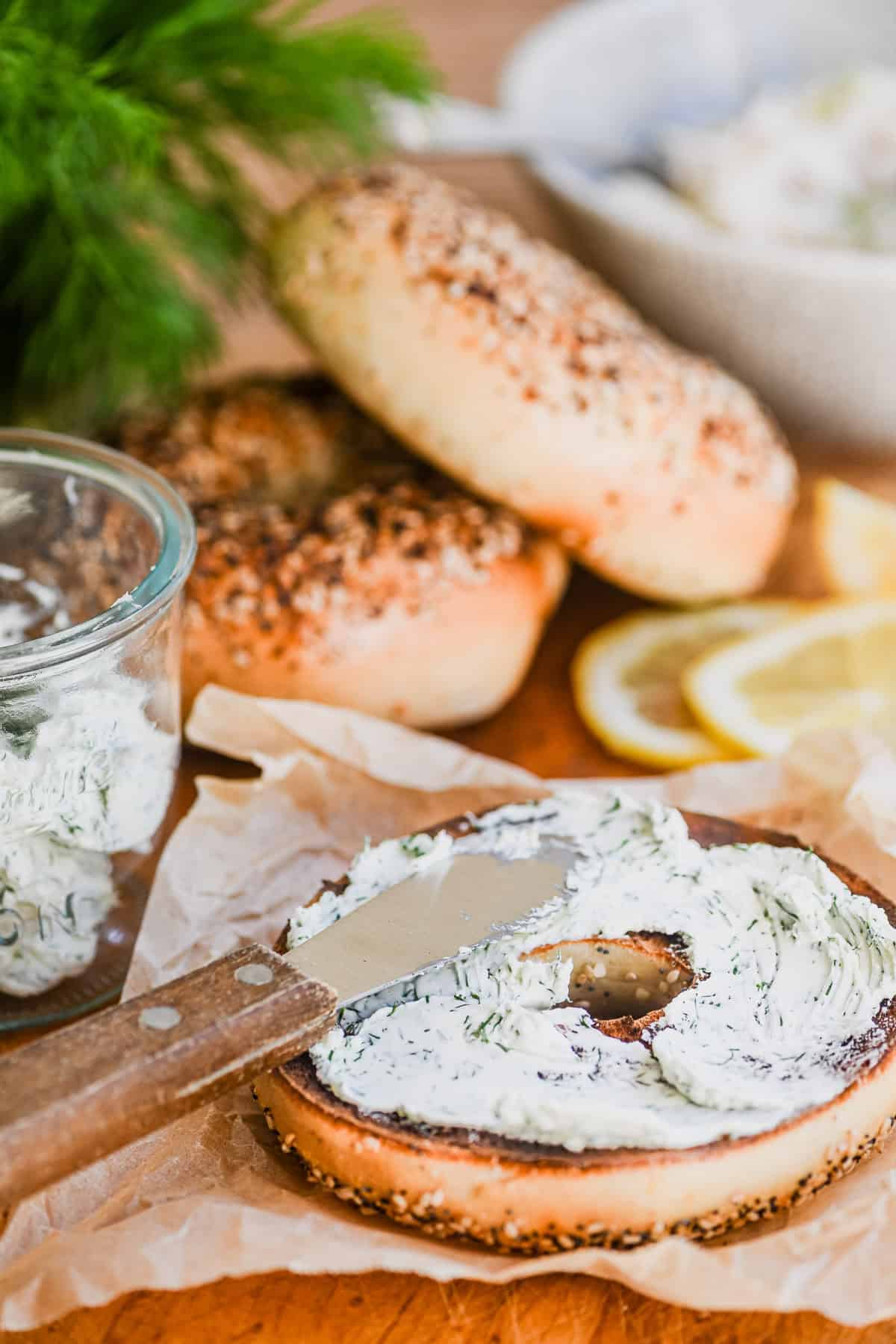 spreading dill cream cheese on bagel.