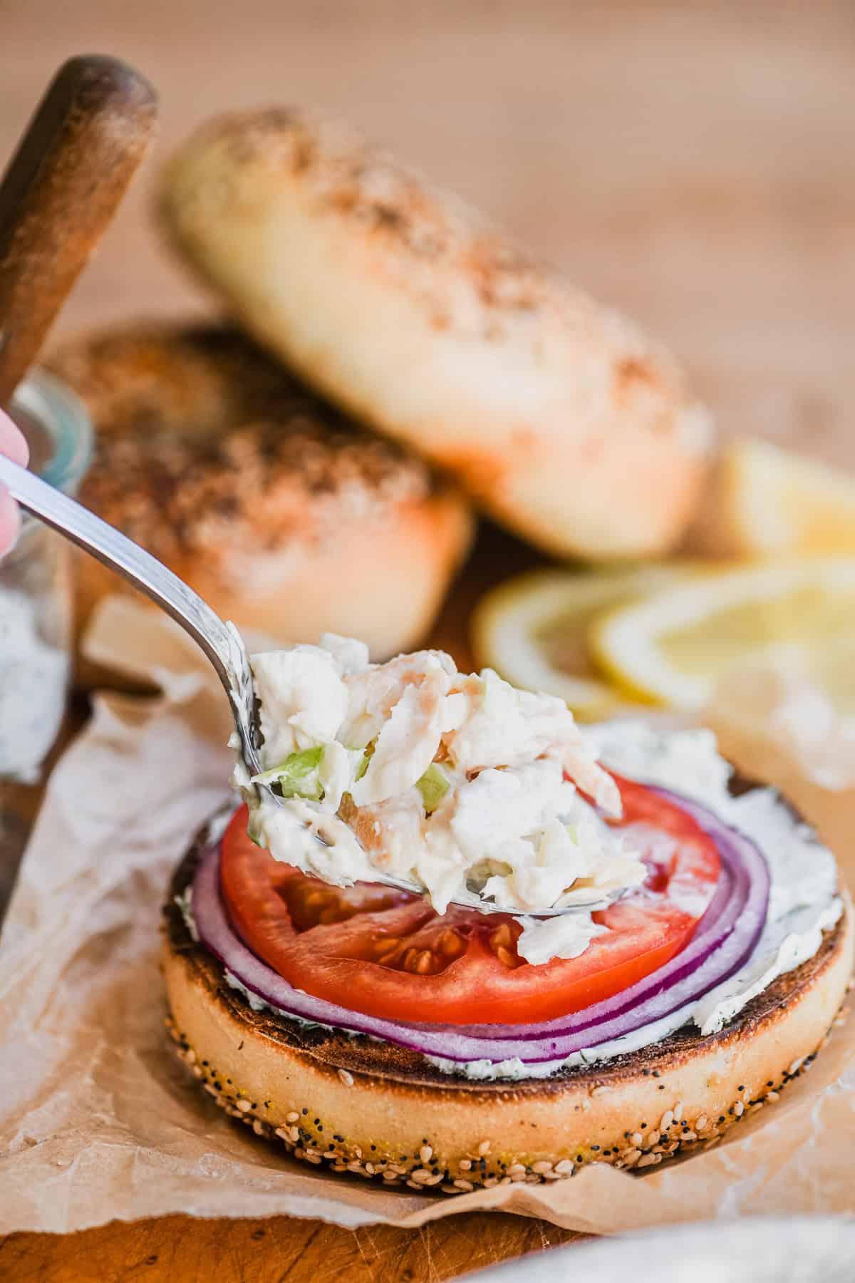 Spooning smoked whitefish salad on a bagel.