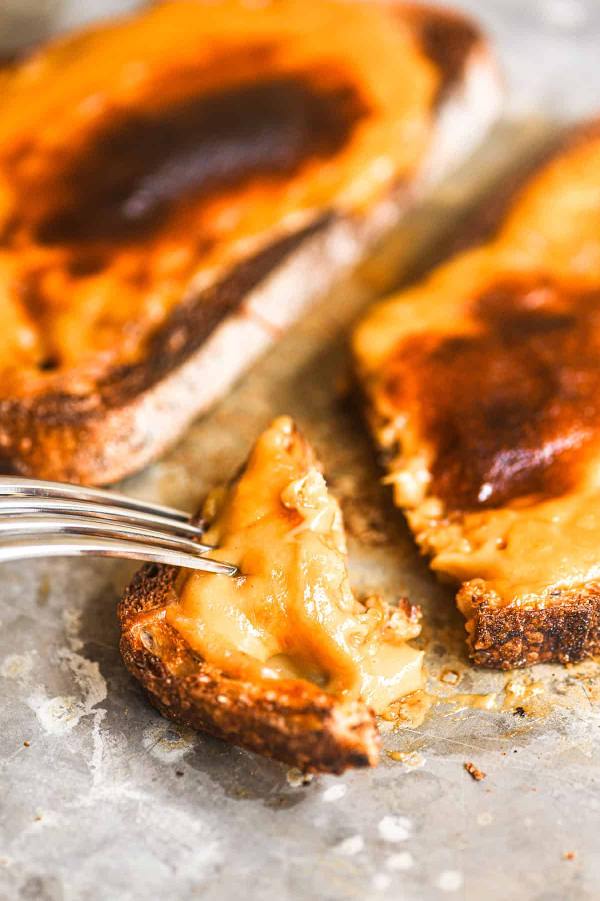 Slicing into Welsh Rarebit on a baking sheet,