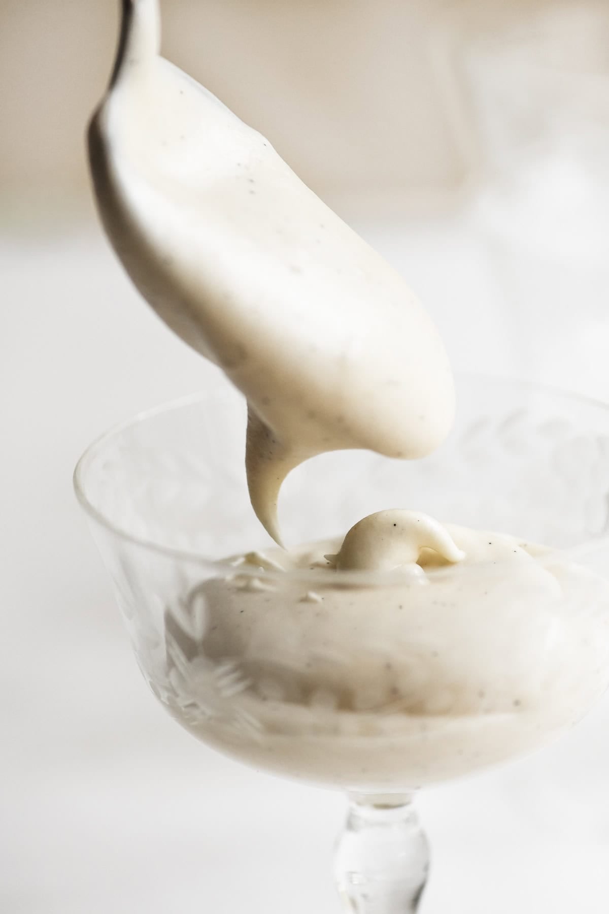 spooning white chocolate mousse into a dessert glass.