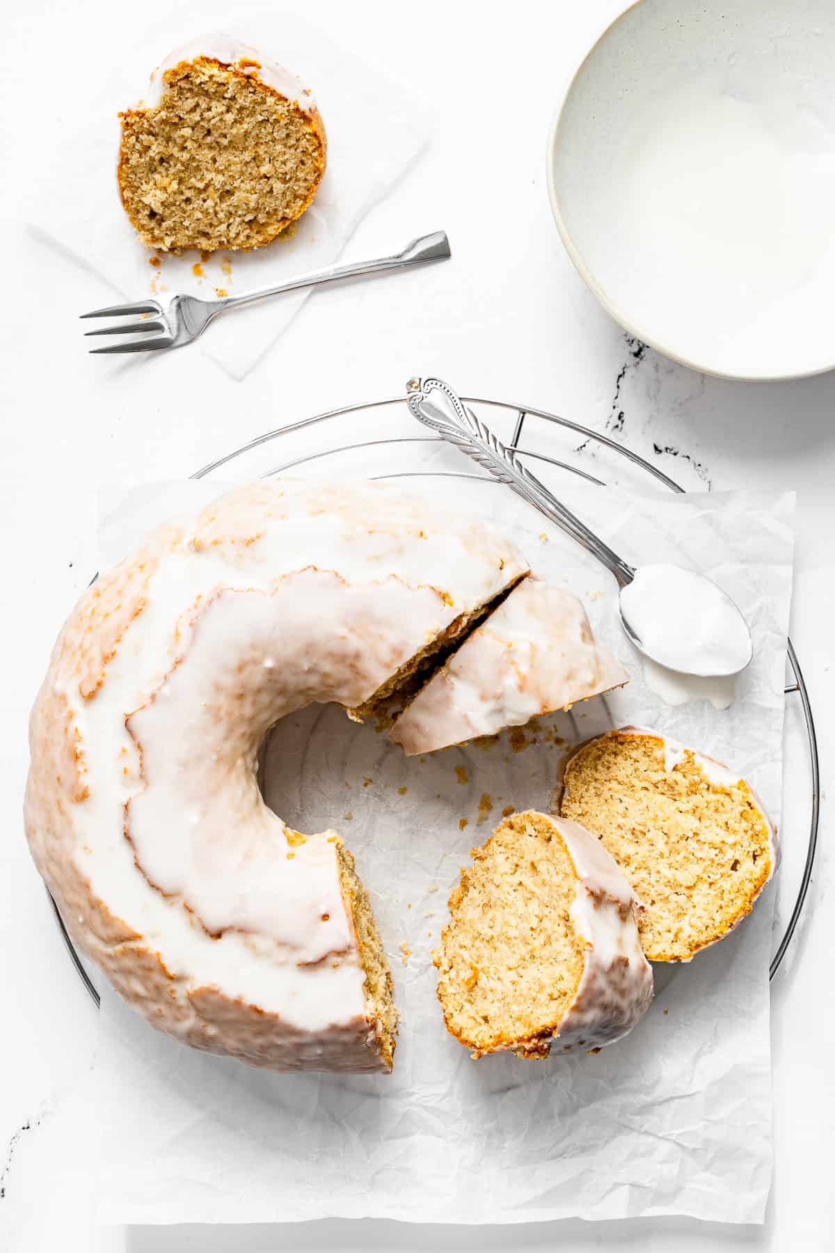 glazed old fashioned doughnut cake on a plate with slices cut.