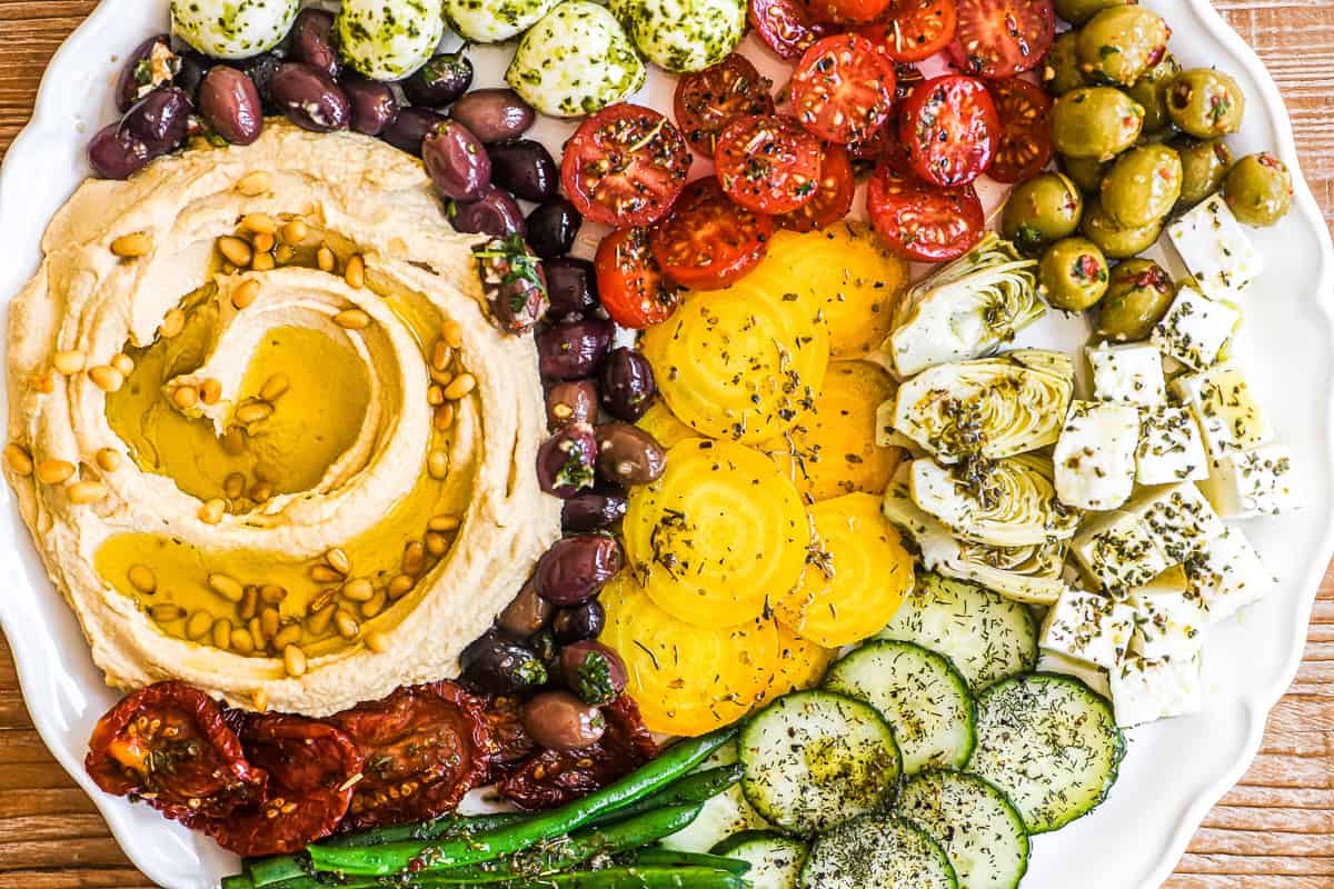hummus mezze platter with colorful marinated veggies and cheese.