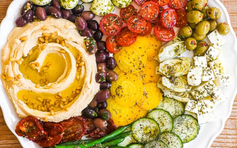 hummus mezze platter with colorful marinated veggies and cheese.