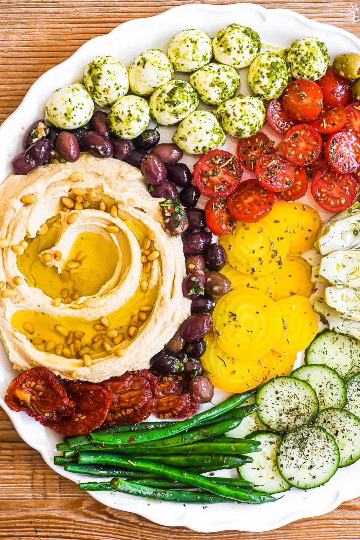 hummus mezze platter with colorful marinated veggies, olives, and cheese.