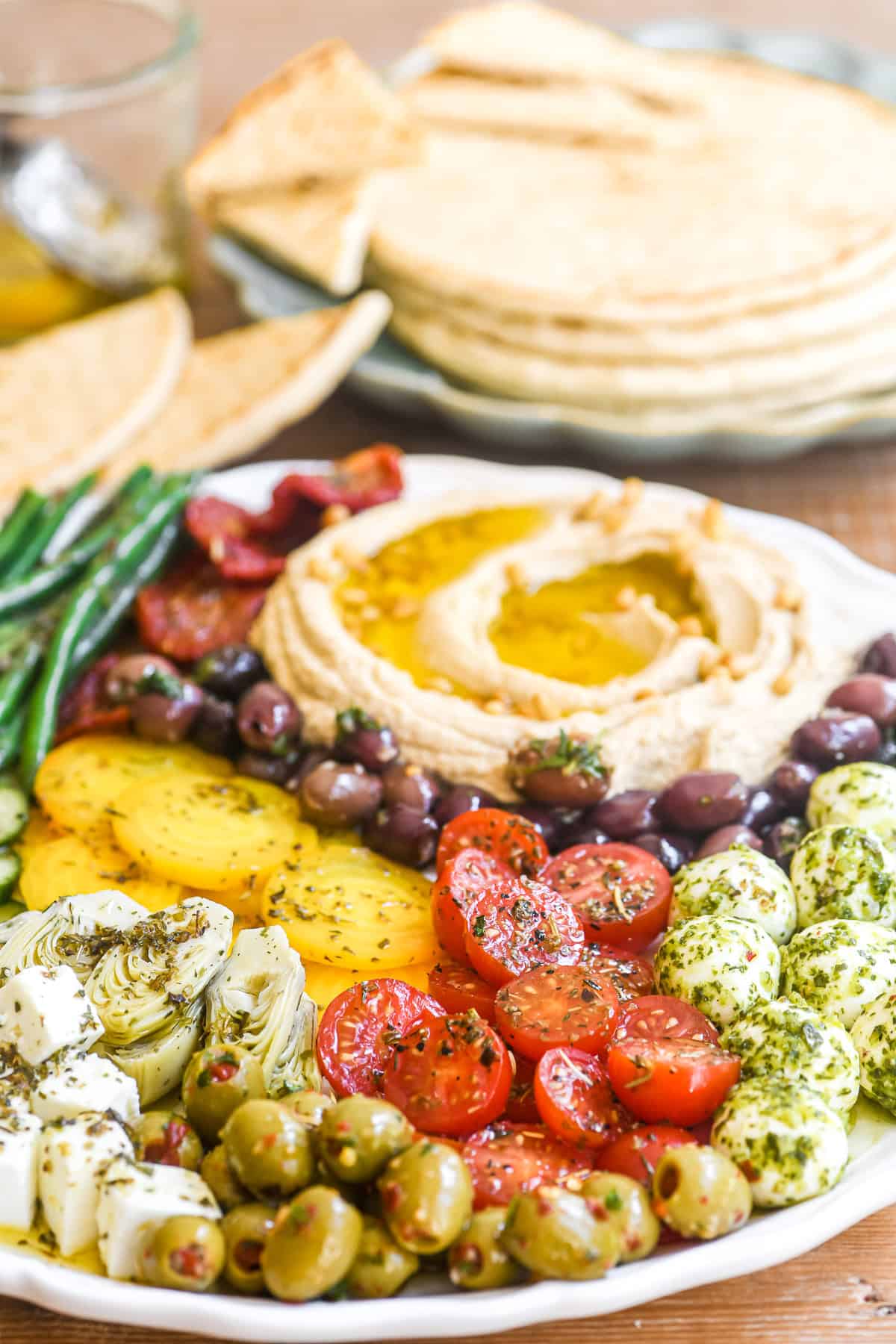 hummus platter with marinated veggies and cheeses.