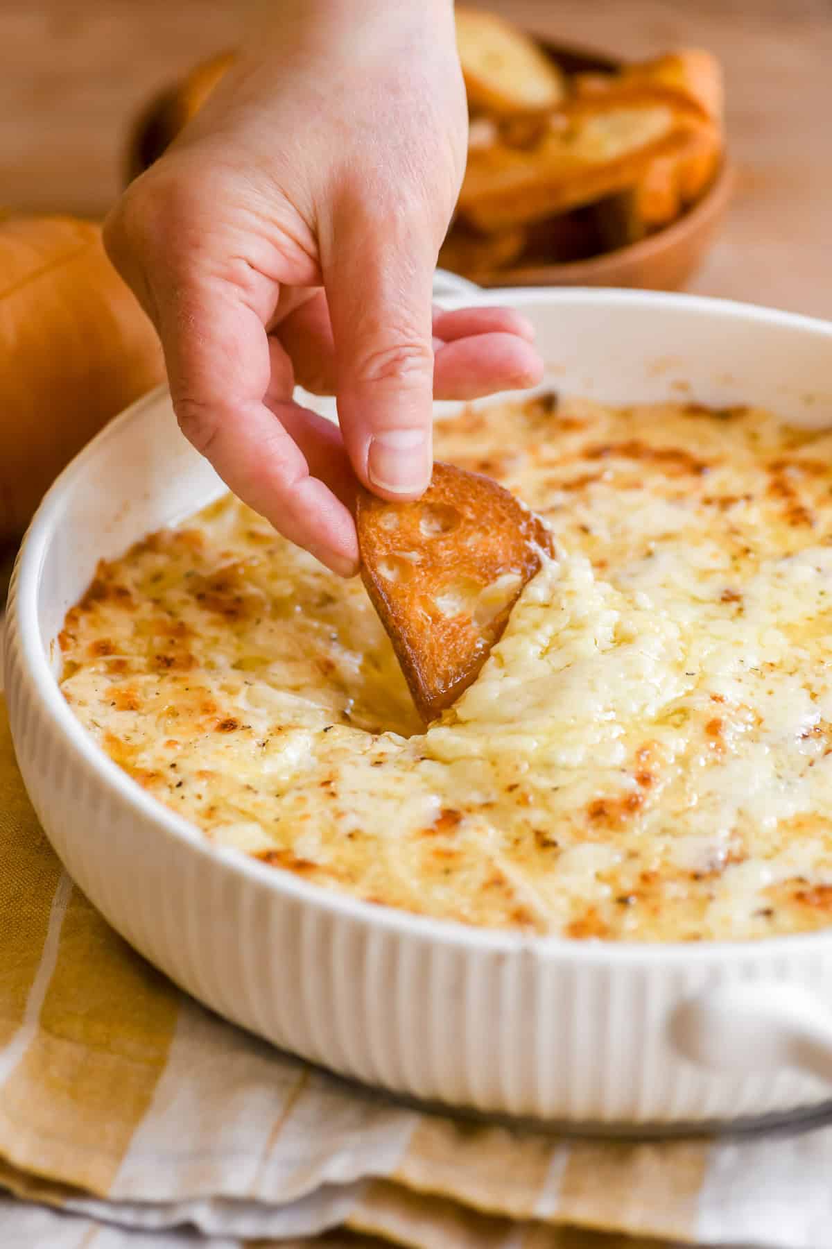 scooping sweet Vidalia onion dip with a slice of toasted baguette,.