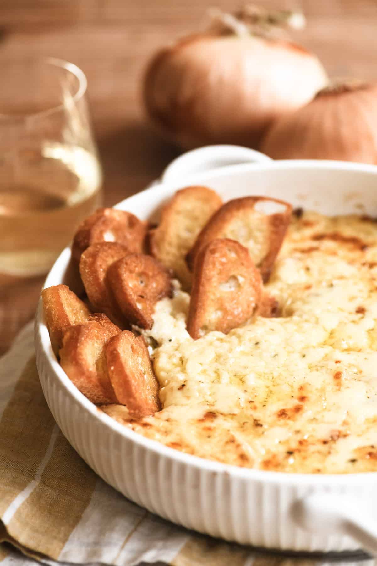 Baked Vidalia onion dip in a white casserole dish with toasted bread.