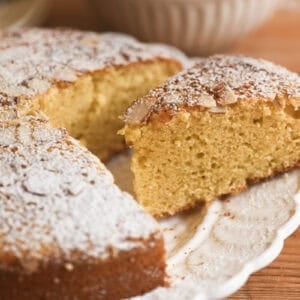 taking a slice of almond olive oil cake from a plate.