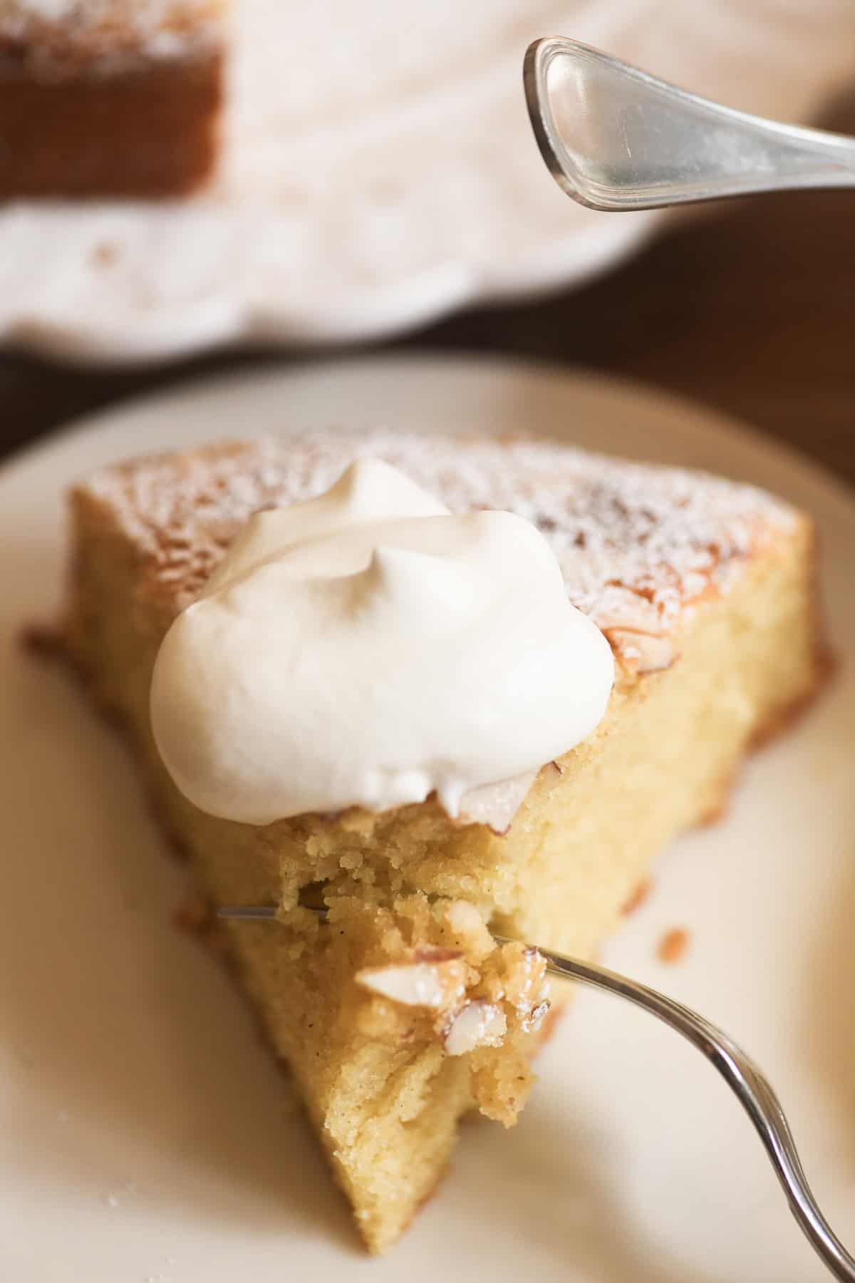 Slice of almond olive oil cake with fork taking a bite.