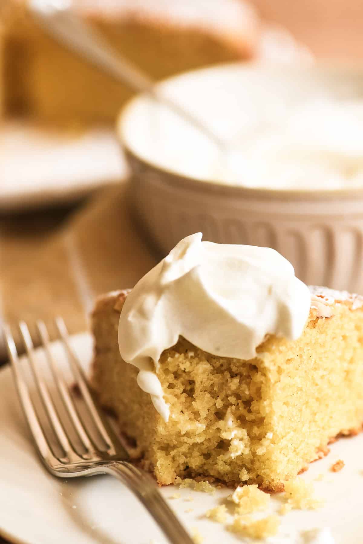 Eating a slice of almond olive oil cake topped with whipped cream.