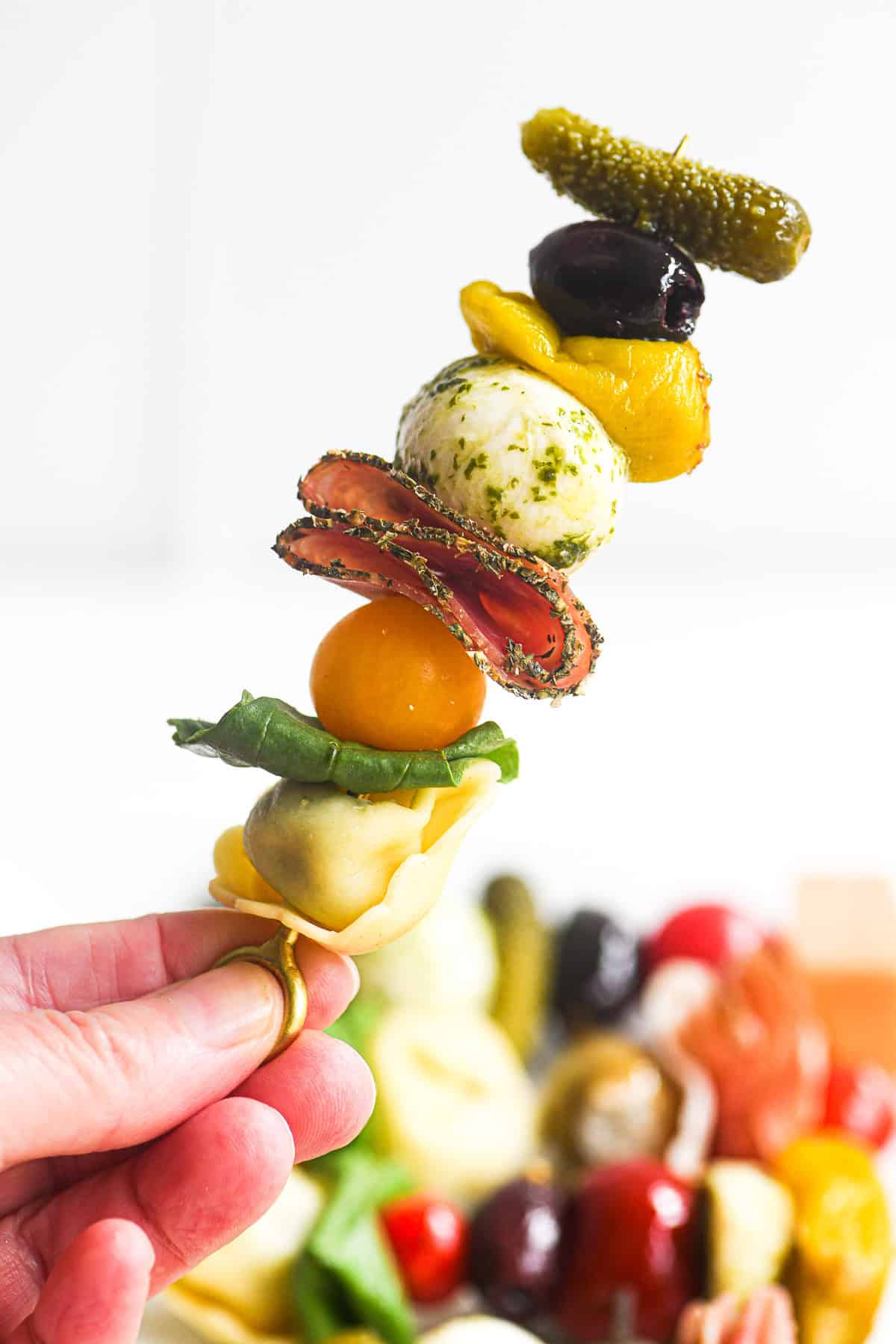 hand holding a single antipasto skewer up.