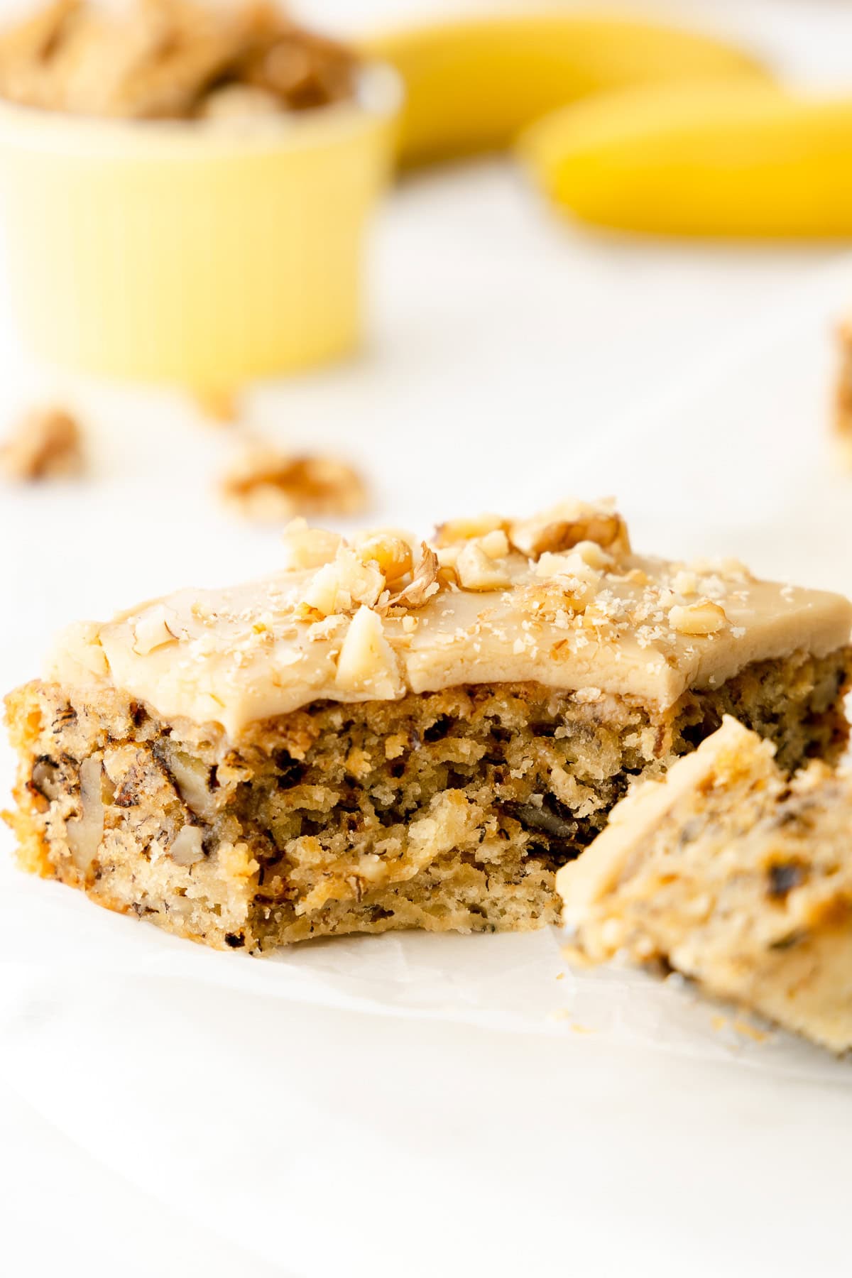 A piece of banana walnut cake with caramel frosting with bite taken.