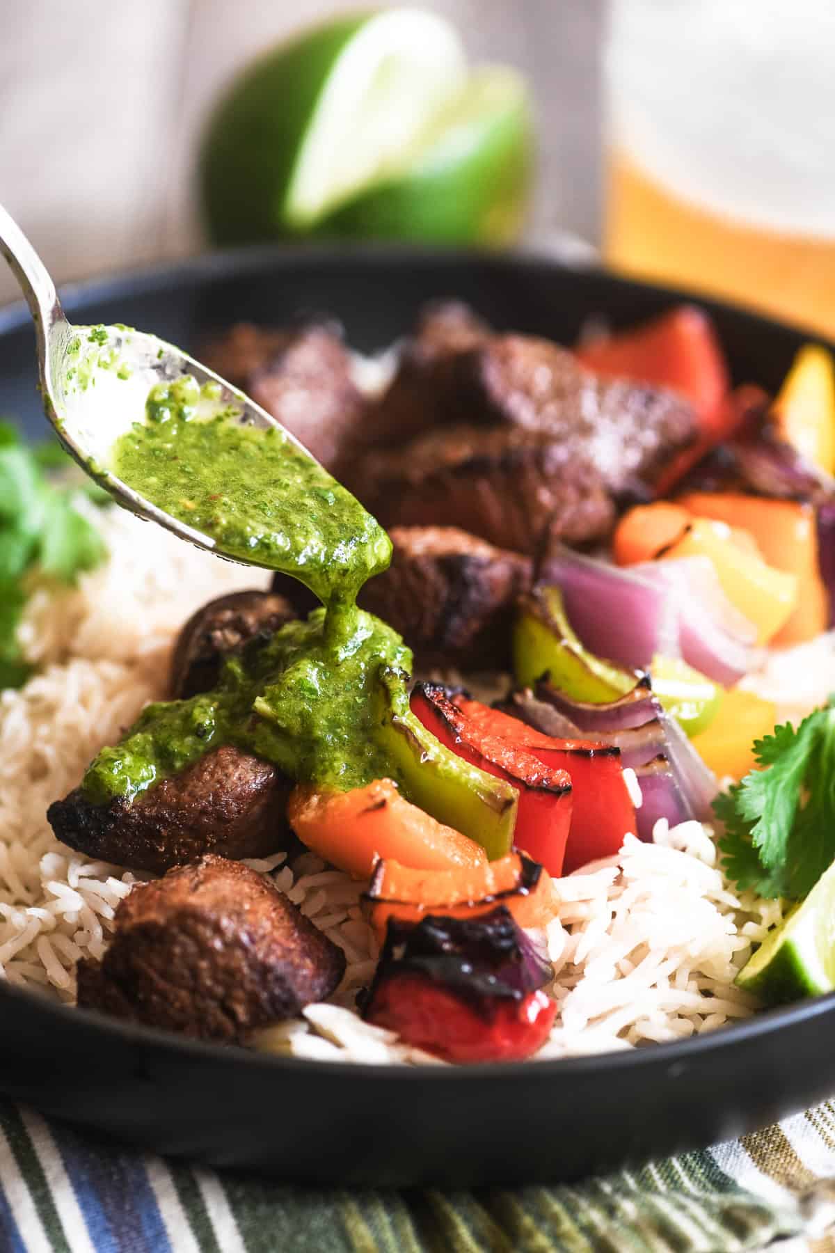 Spooning chimichurri sauce onto fajita skewer bowl.