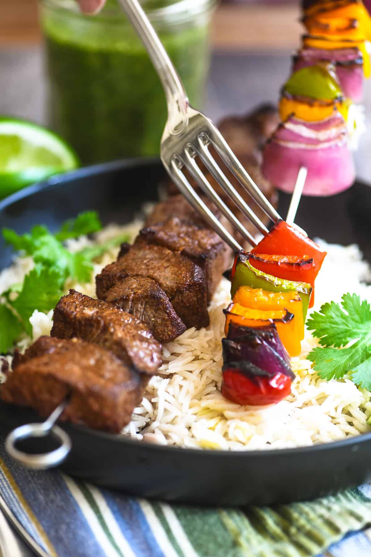 Fork pushing veggies off a fajita skewer.