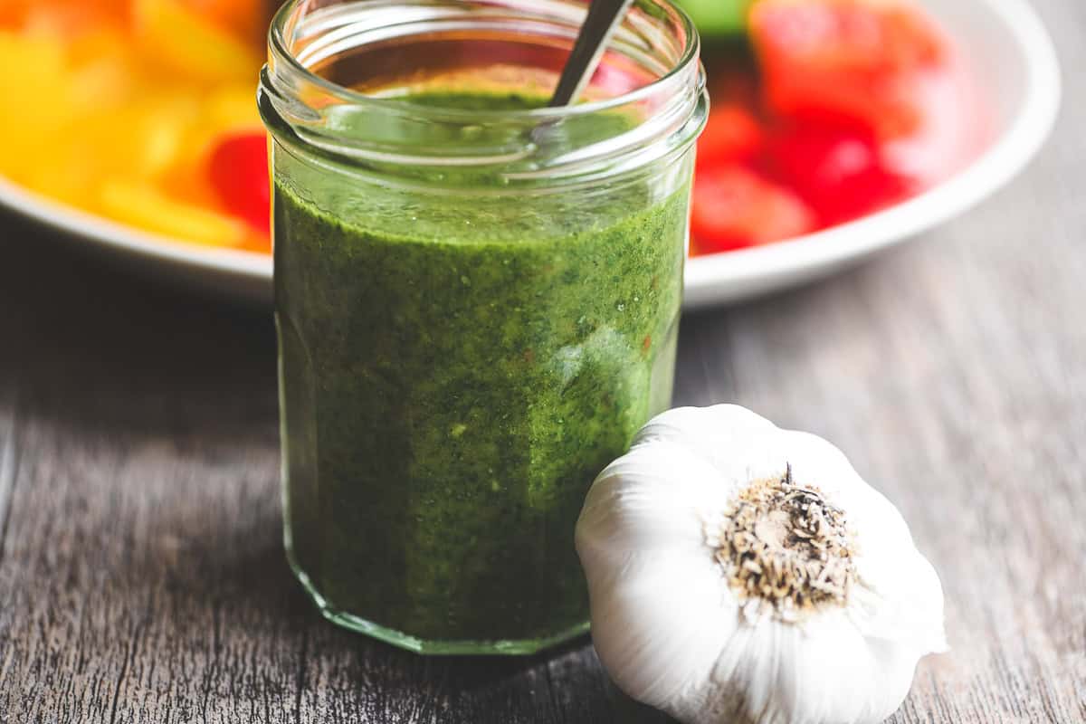 chimichurri sauce in a small jar with garlic.