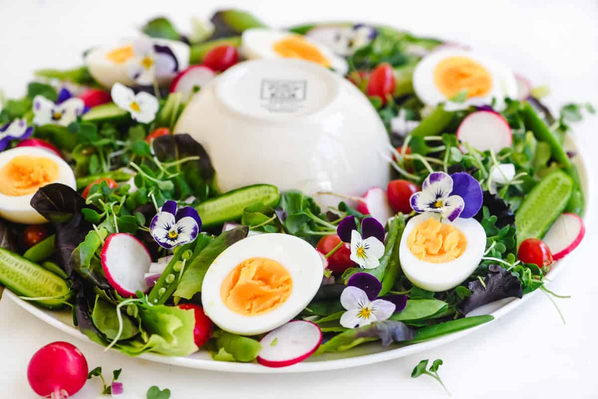 making a wreath salad on a round platter with an overturned bowl in the center.