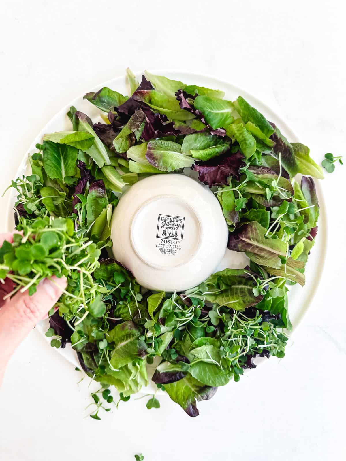 placing lettuce on a platter for a wreath salad.