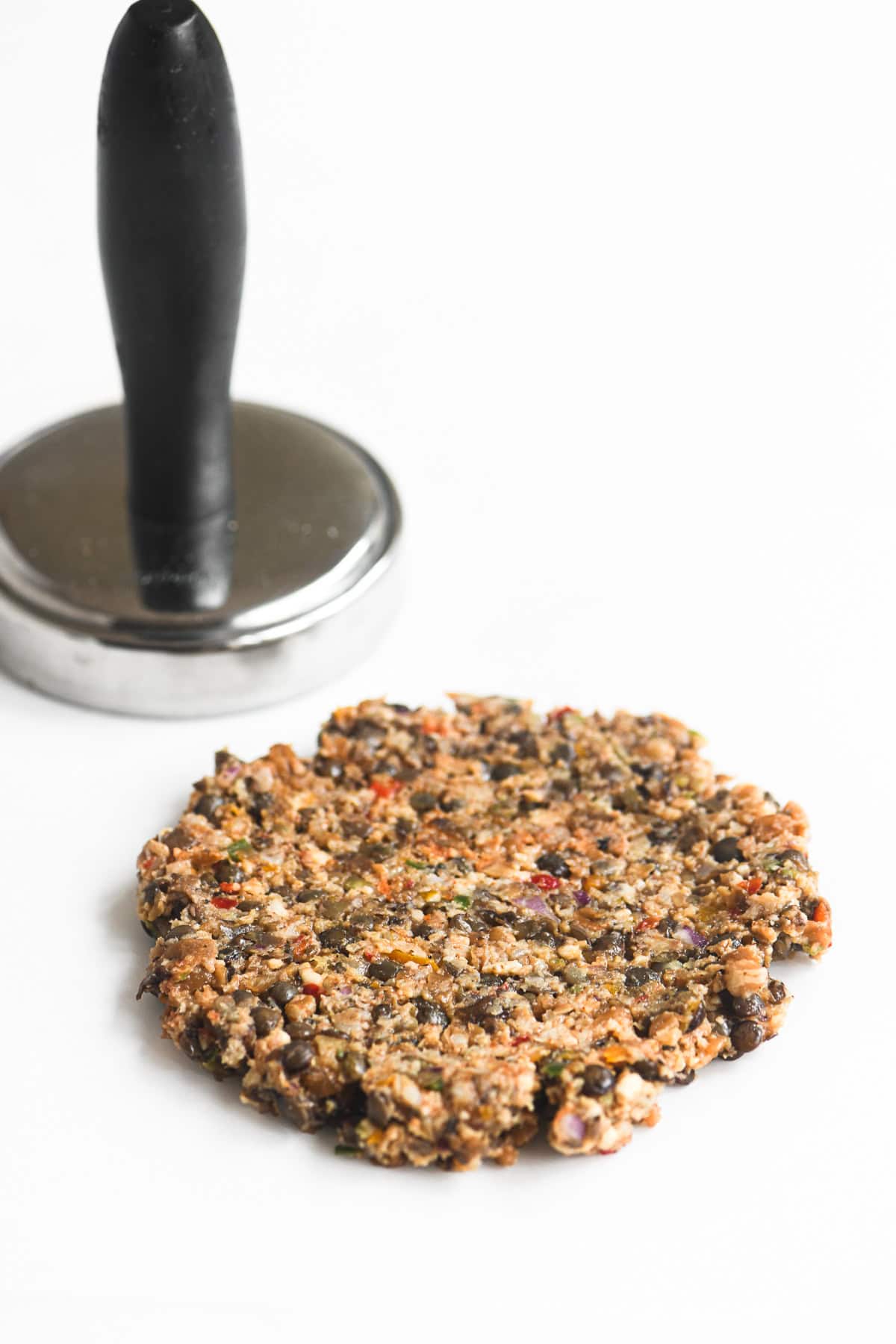 smashing a veggie smashburger with a meat pounder.