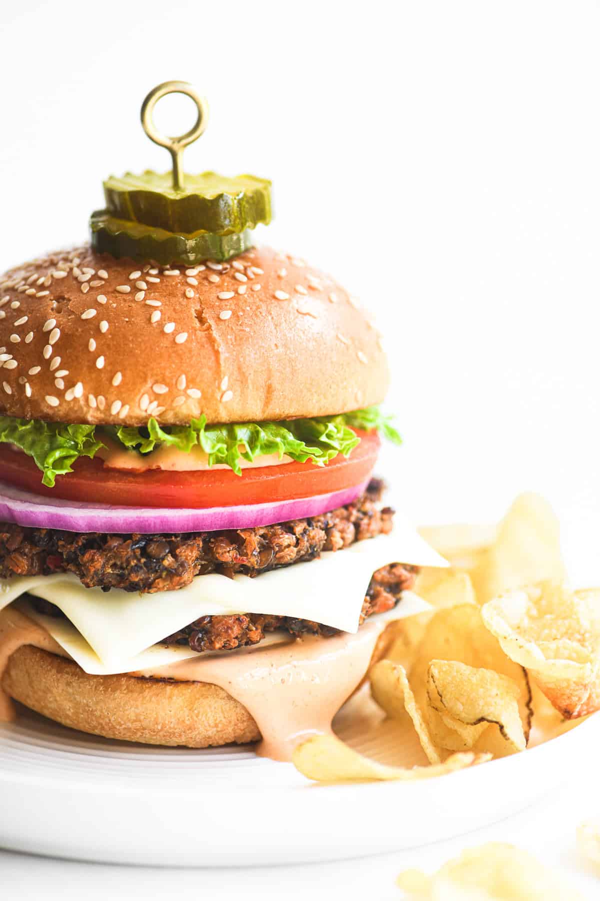 veggie smash burger with all the fixings on a plate with potato chips.