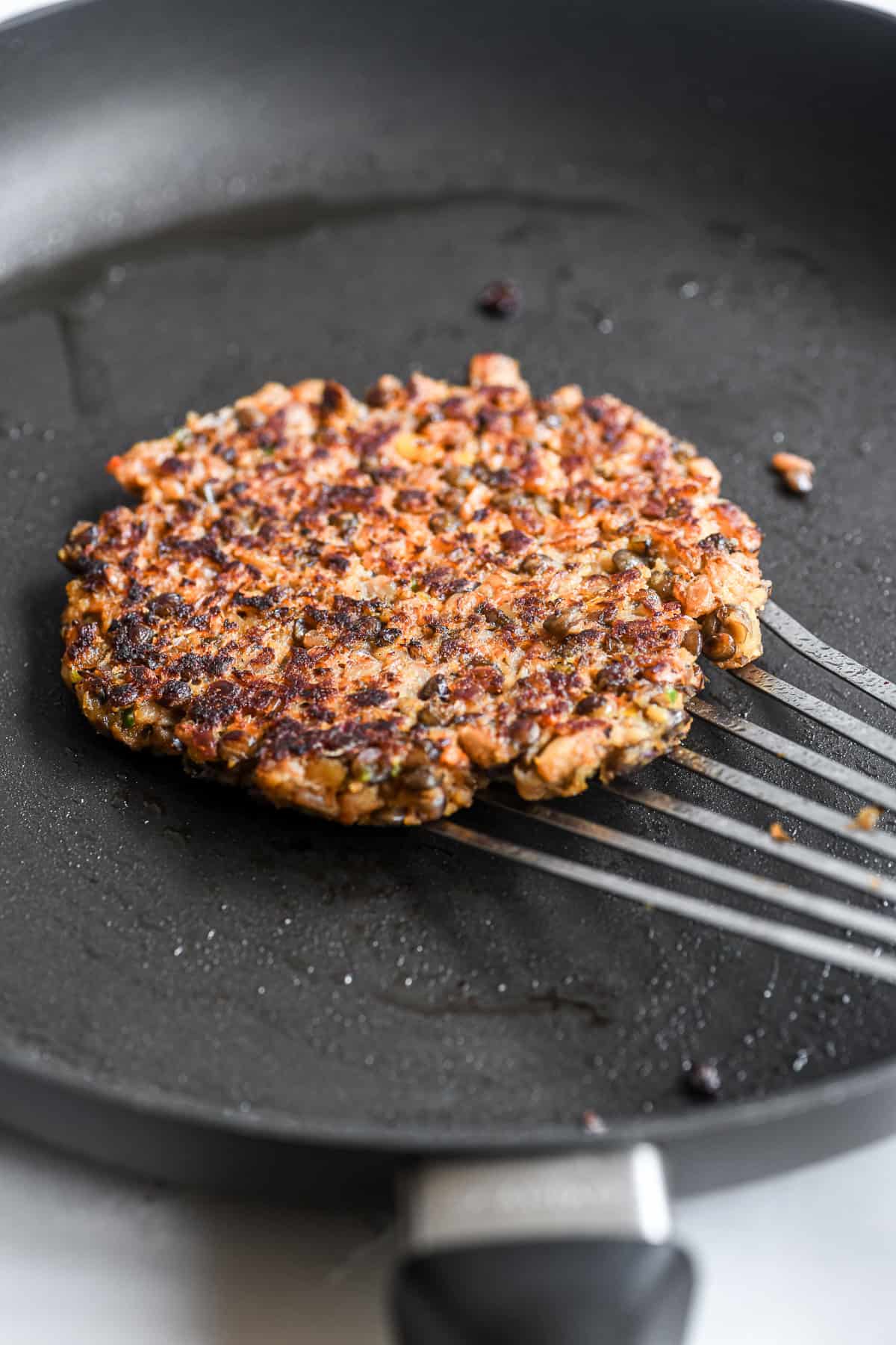 veggie smashburgers, cooking in a pan.