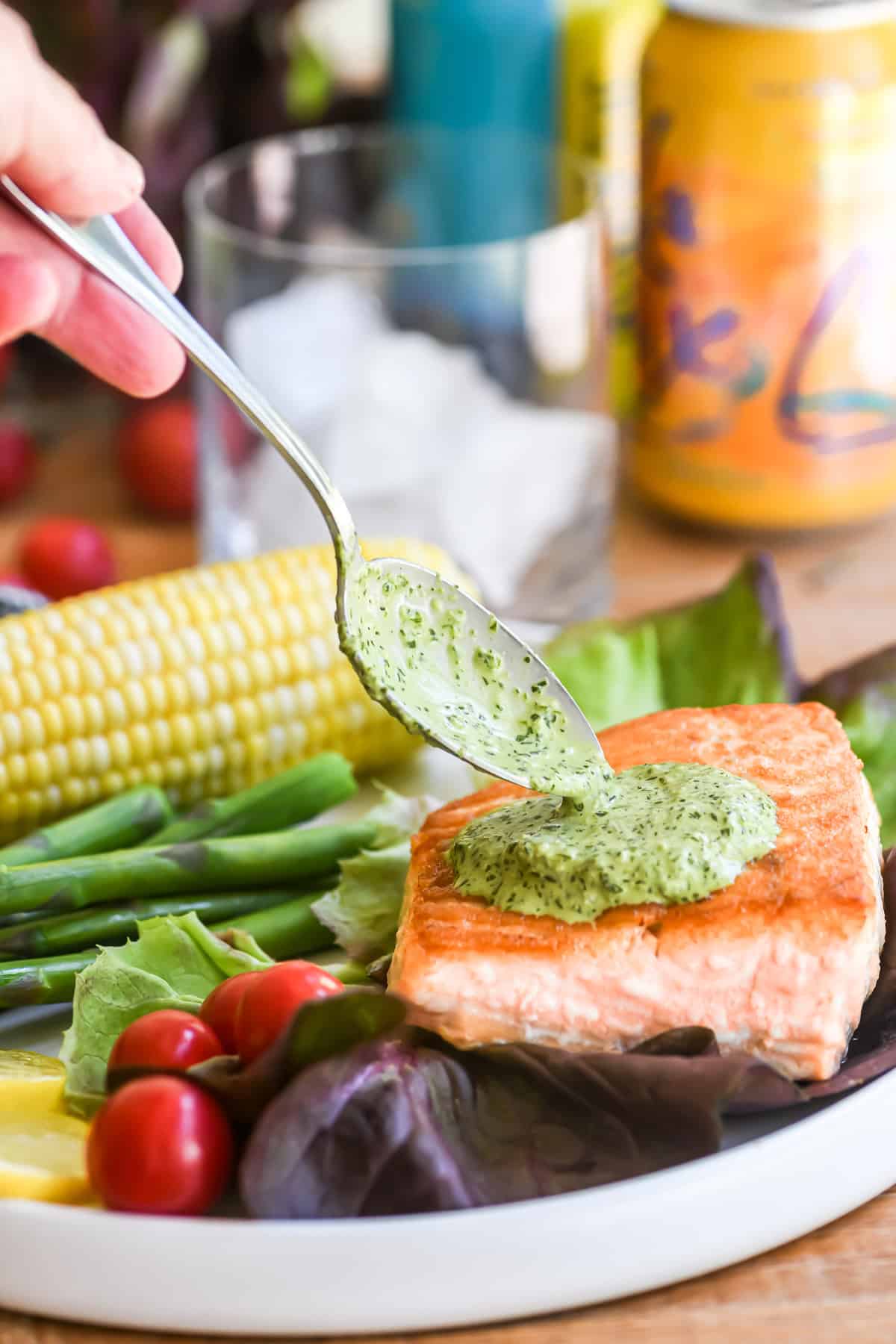 Spooning green goddess sauce over salmon.