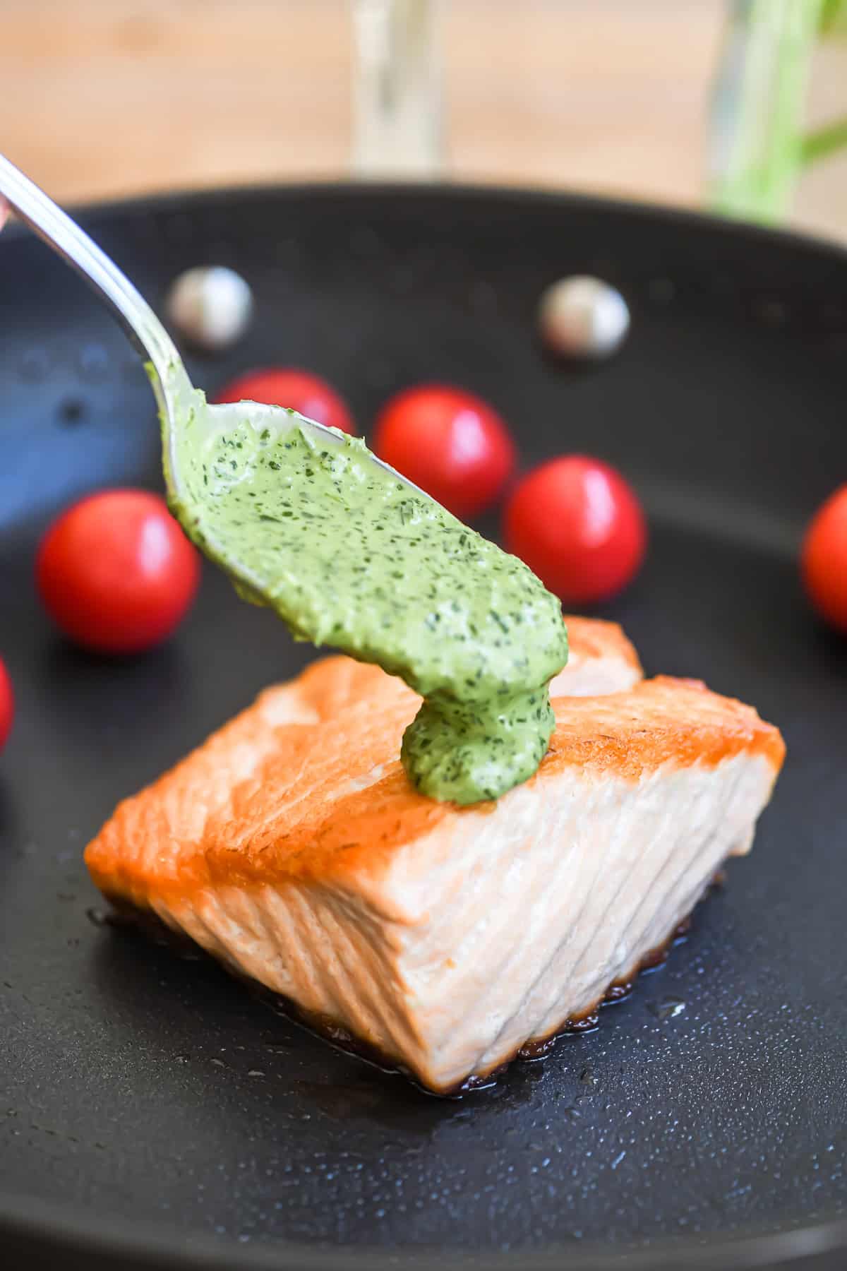 spooning green goddess sauce on salmon