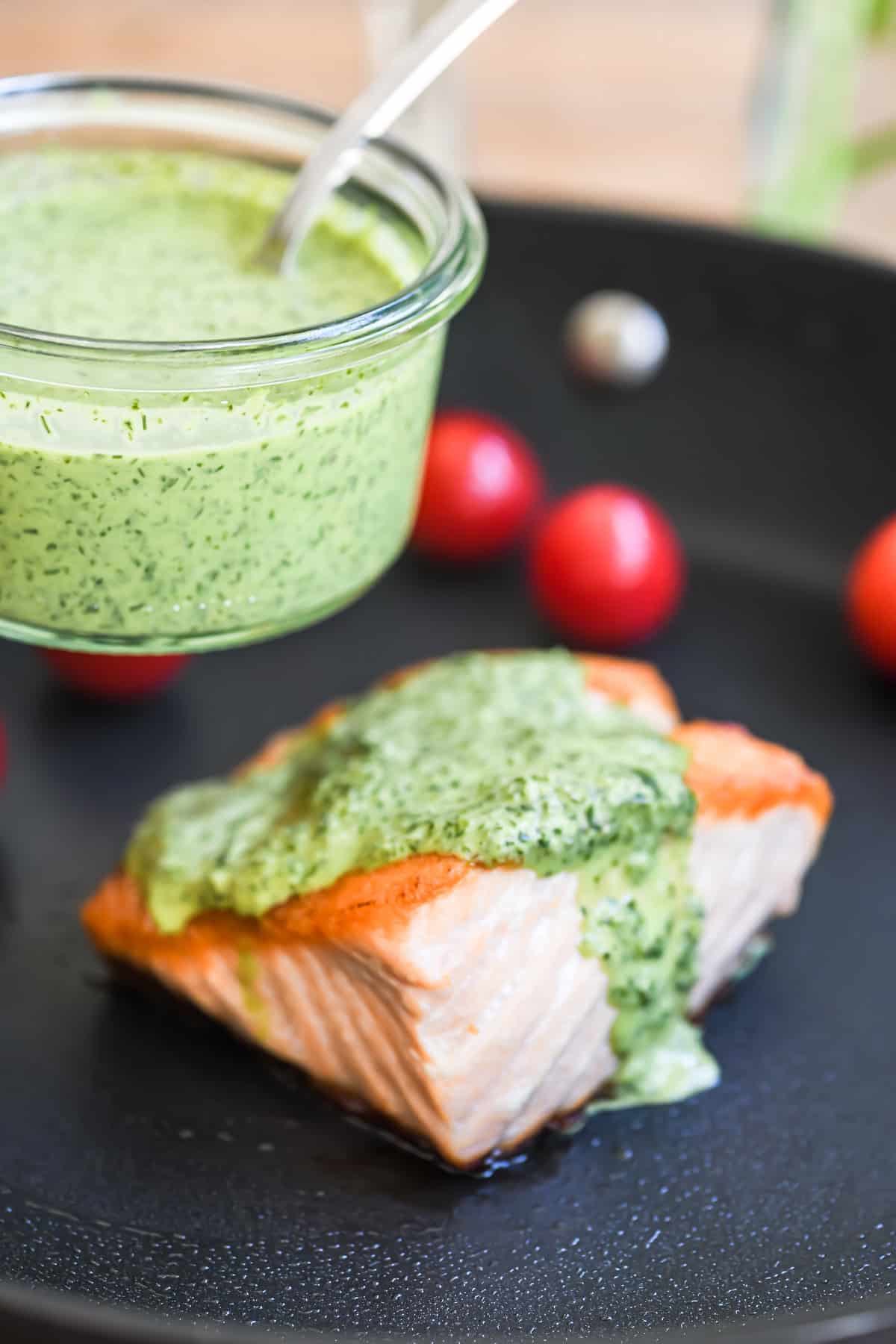 green goddess sauce dripping from a piece of seared salmon.
