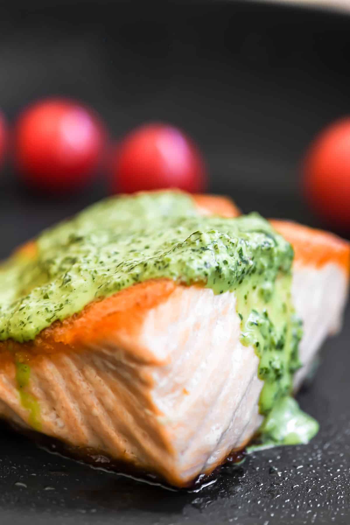 A piece of seared salmon in the pan, topped with green goddess sauce.