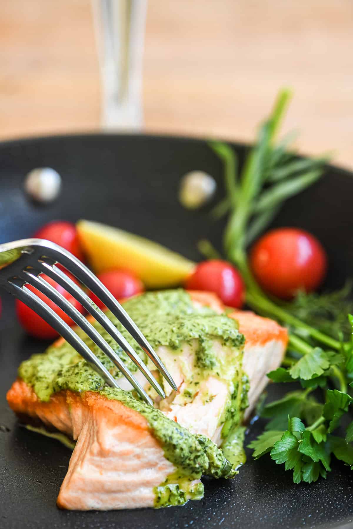 Green goddess salmon in a skillet with herbs.