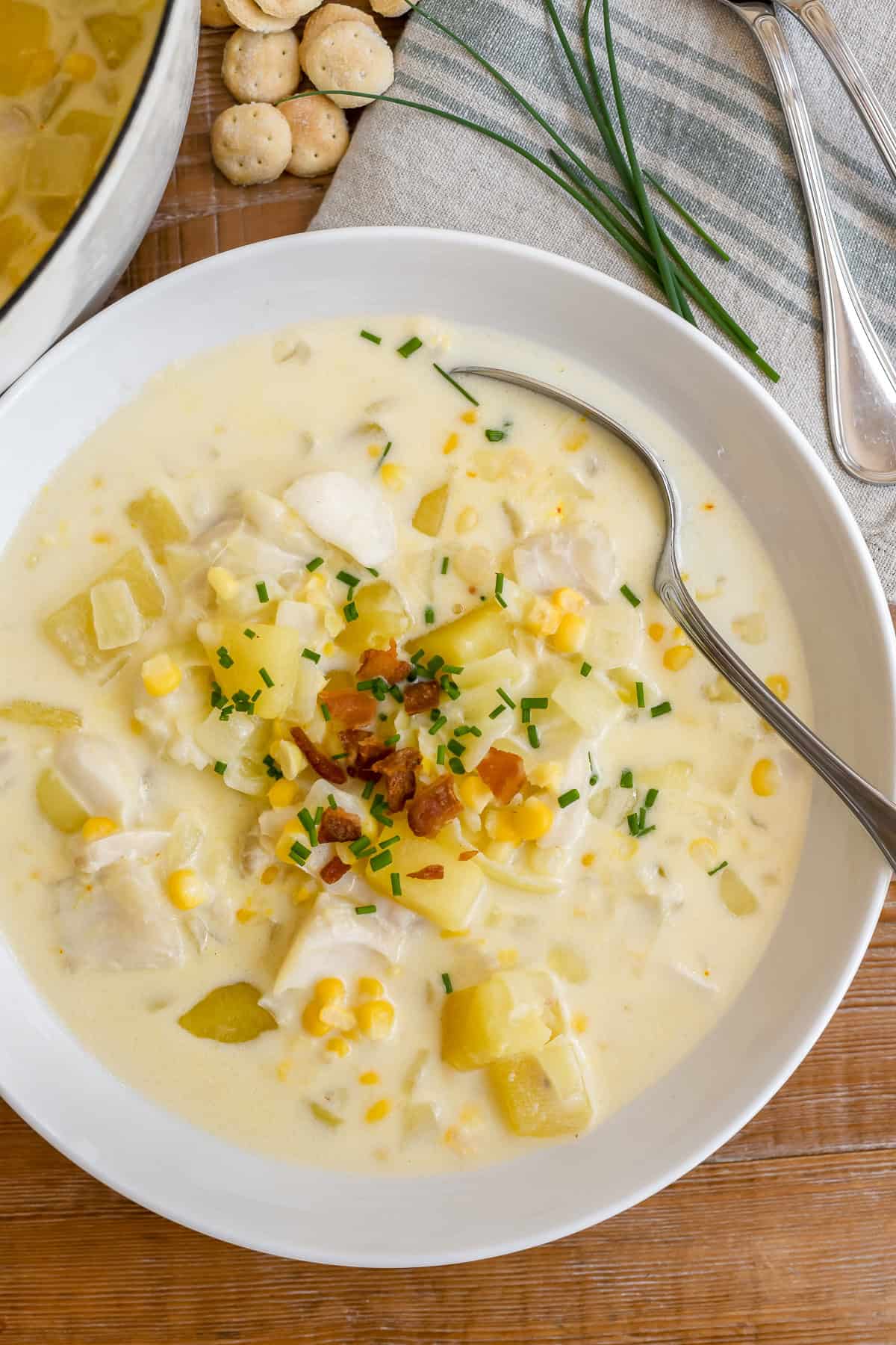 A bowl of New England fish chowder with bacon, chives, and oyster crackers.