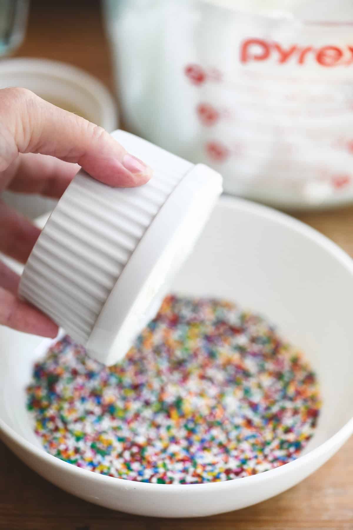 Getting ready to dip a dot cake into nonpareil sprinkles.