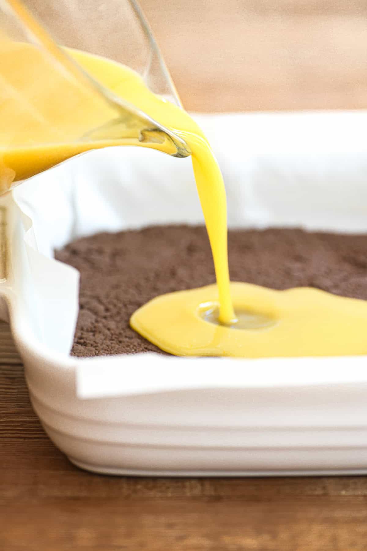 Pouring lemon filling onto chocolate black bottom crust.