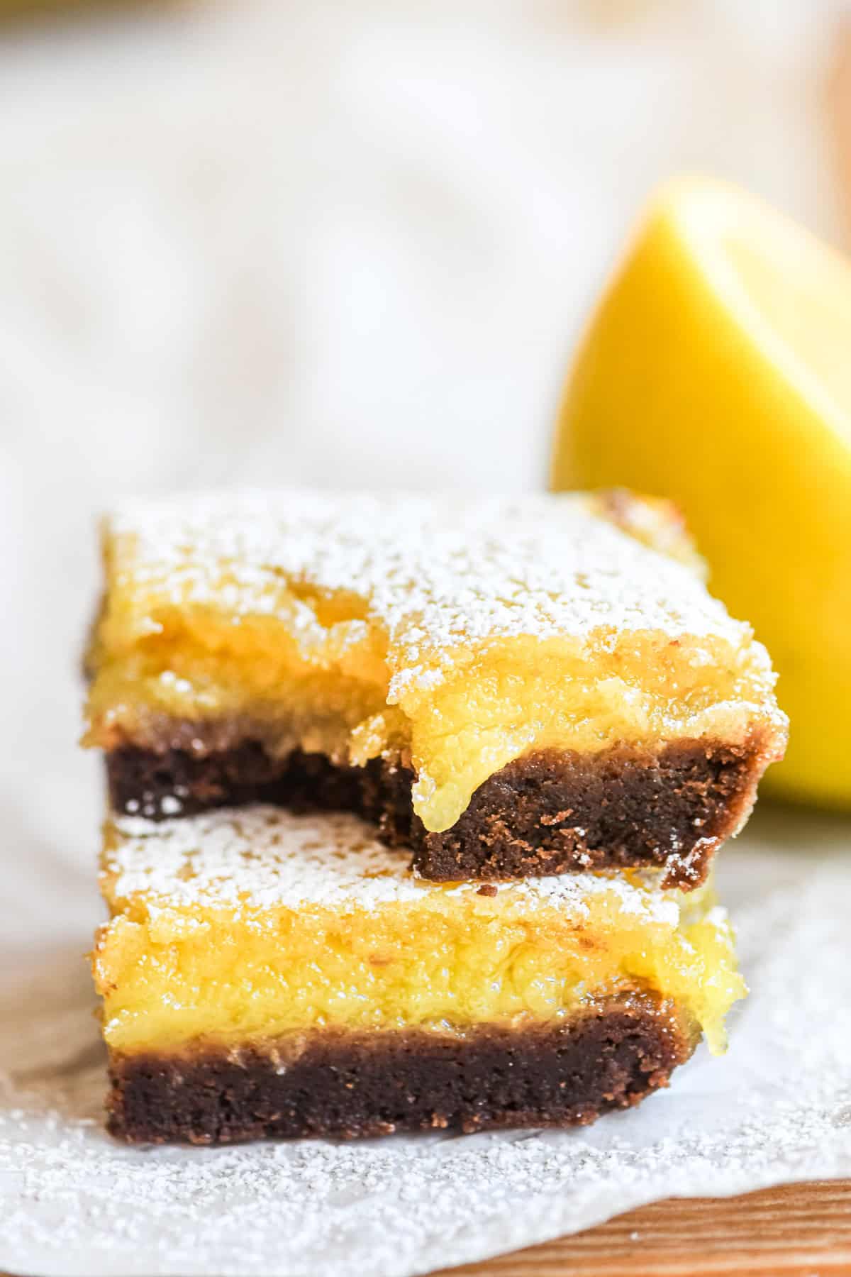 Black bottom lemon bars, stacked, with bite taken and lemon filling oozing.