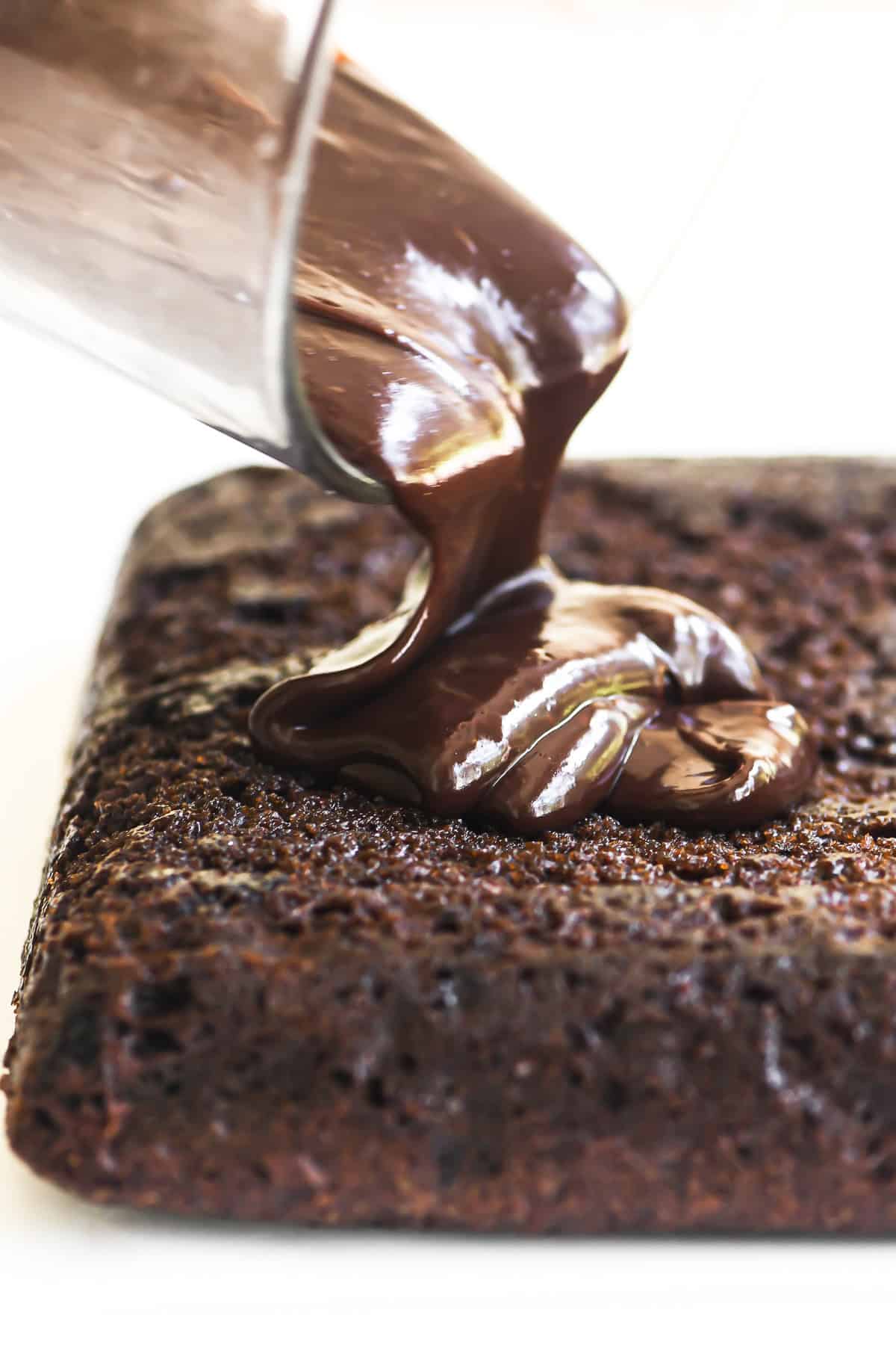 Pouring chocolate ganache over a chocolate cake.